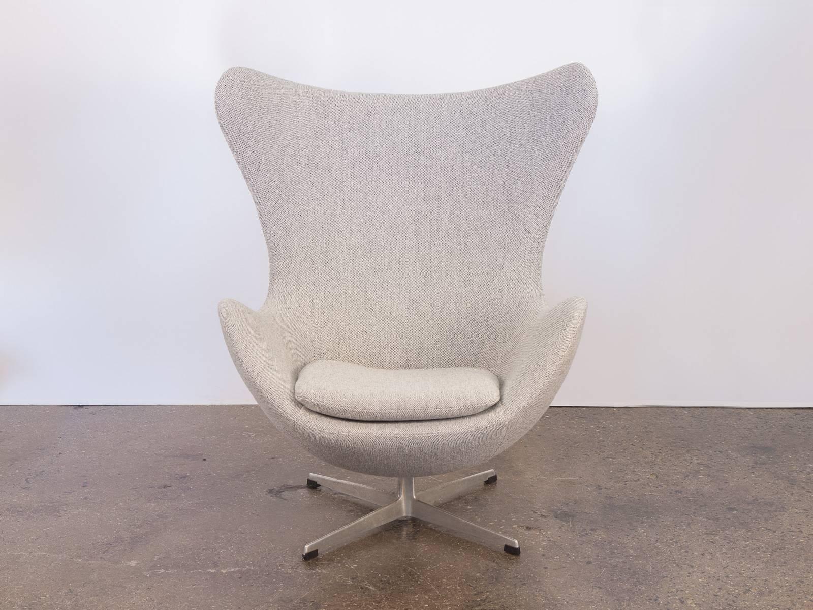 The iconic Egg chair and matching footstool designed by Arne Jacobsen in 1958. Our chair dates to the 1960s and has been meticulously upholstered in a textured, pale gray Hallingdal by Kvadrat wool. Supremely comfortable. Swiveling four-star base on