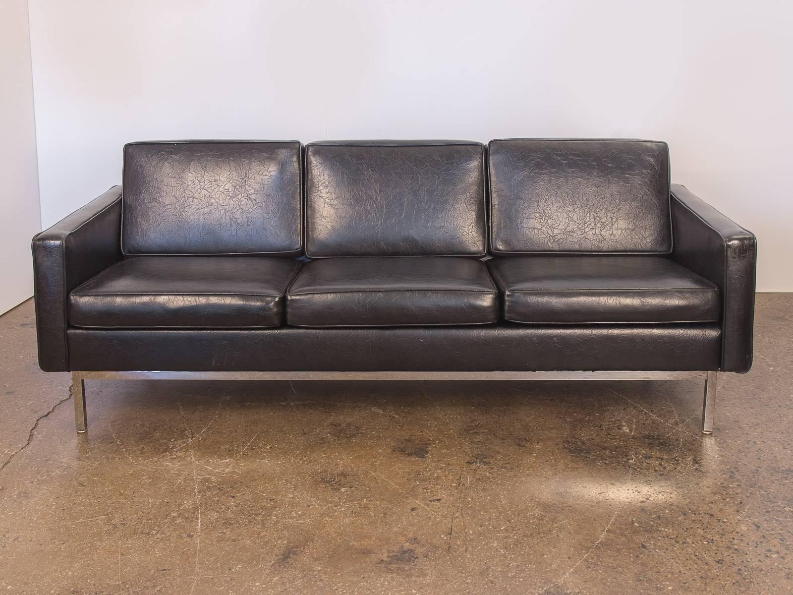 1990s, black chrome frame sofa for Steelcase. A model relative of the Classic Florence Knoll sofa. This three-seat boasts simple geometry with clean lines. Black textured vinyl is staunch and pliable with one blemish on the left armrest. All other