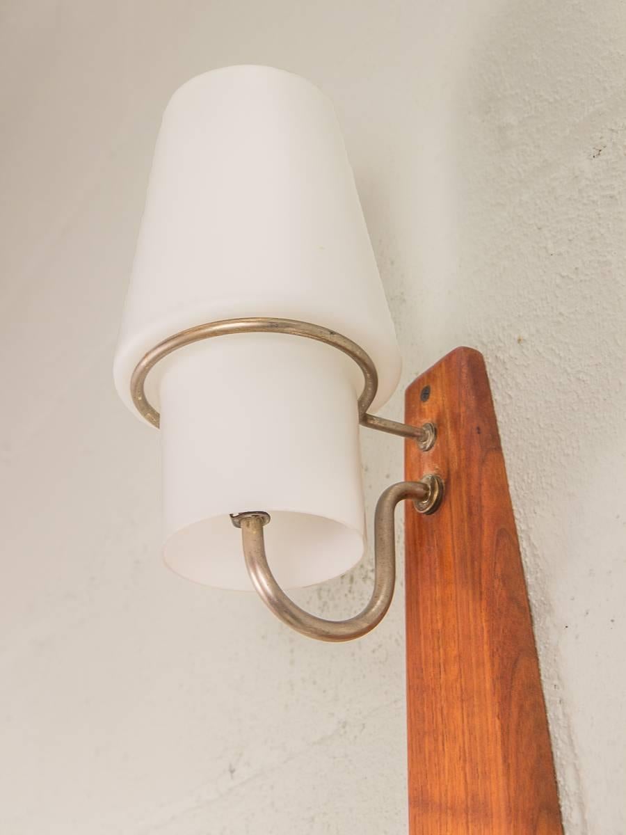 Beautiful Danish modern vertical wall-mounted sconce that features three tapering glass shades. Gleaming, carved teak wood frame is in good vintage condition with some age-appropriate wear. Shades are lovely and have no scratches or chips. The