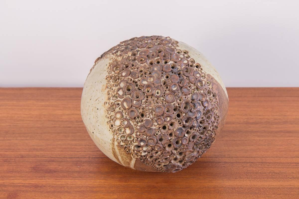 Escultura de esfera de barro hecha a mano. Una bella forma redondeada de cerámica adorna una banda de perforaciones, evocando texturas del mundo natural. La estratificación del esmalte tiene densidades variadas que dan como resultado un bello