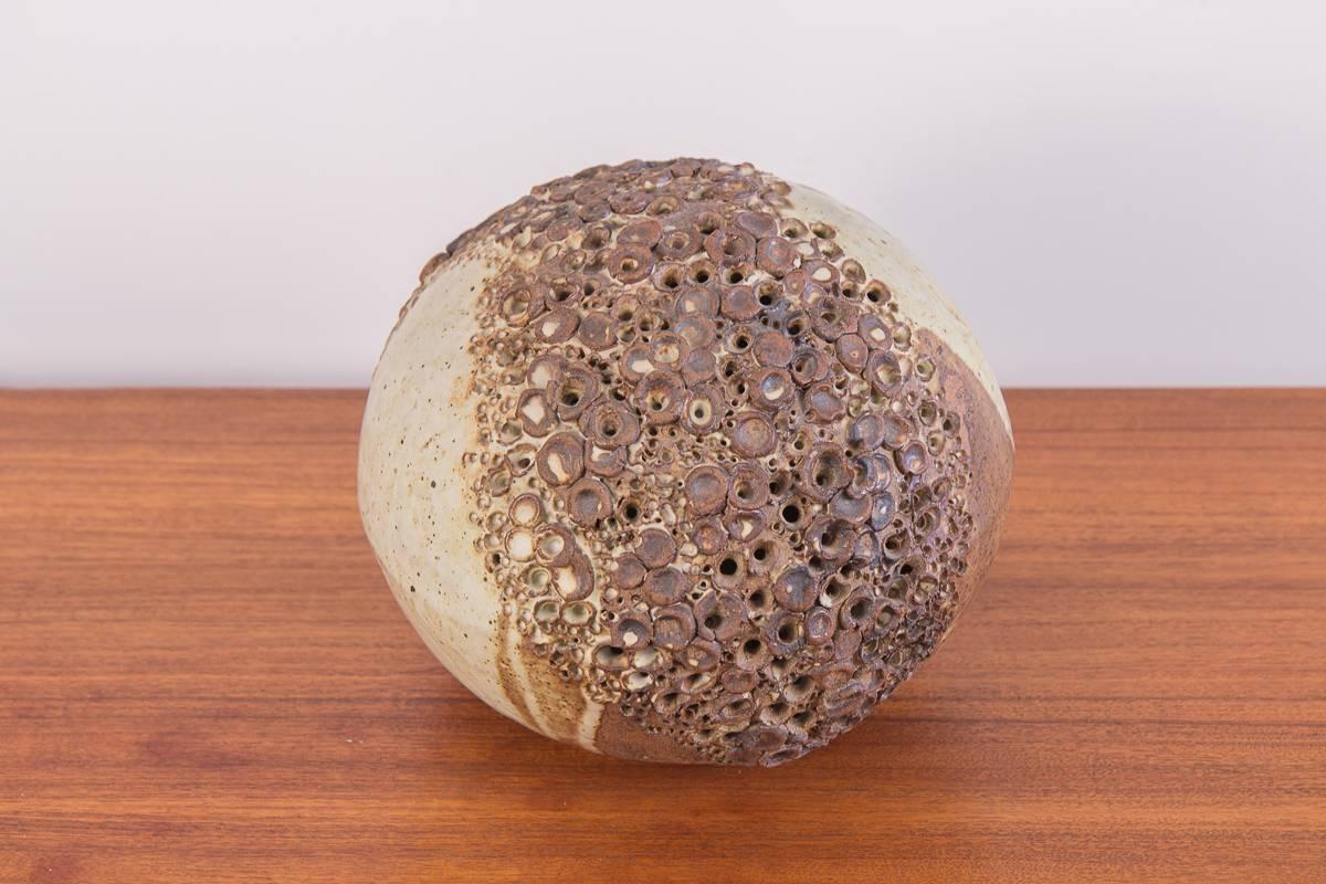 Hand-built earthenware sphere sculpture. Beautiful, rounded ceramic form adorns a band of perforations, evoking textures from the natural world. Glaze layering has variegated densities resulting in a beautiful, irregular matte finish. In excellent