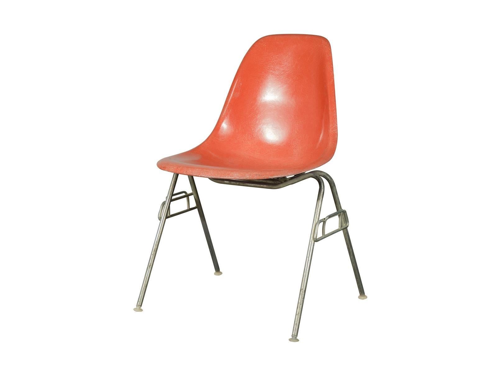 Original 1960s DSS molded fiberglass shell chairs on stacking base, designed by Charles and Ray Eames for Herman Miller. Gleaming orange shells are in original condition, each with a distinct thready texture.  Shown here mounted on stacking base,