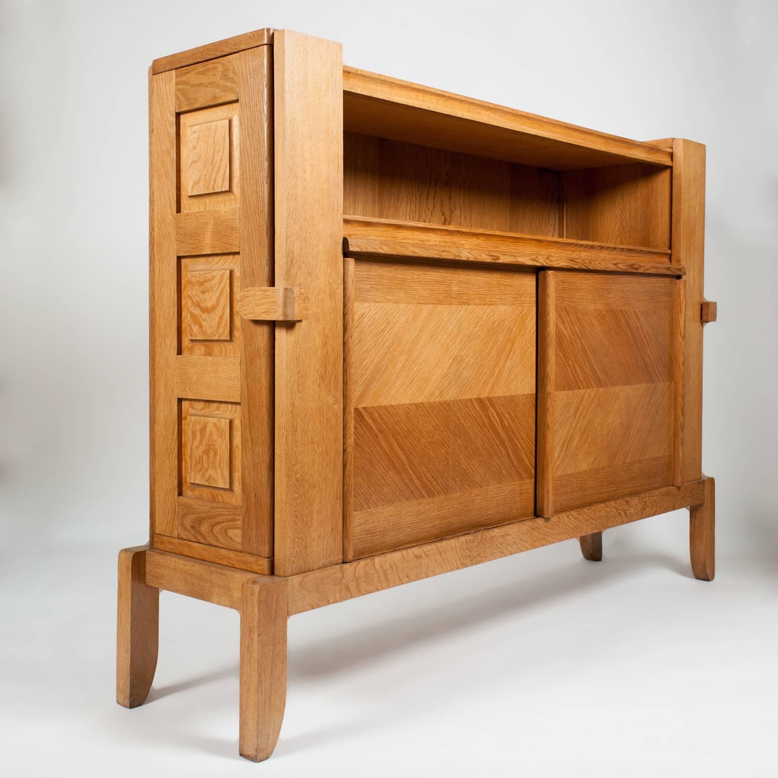 Sideboard designed by Guillerme et Chambron in solid oak with beautiful patina, with side doors that hide small shelves, central space with two sliding doors.