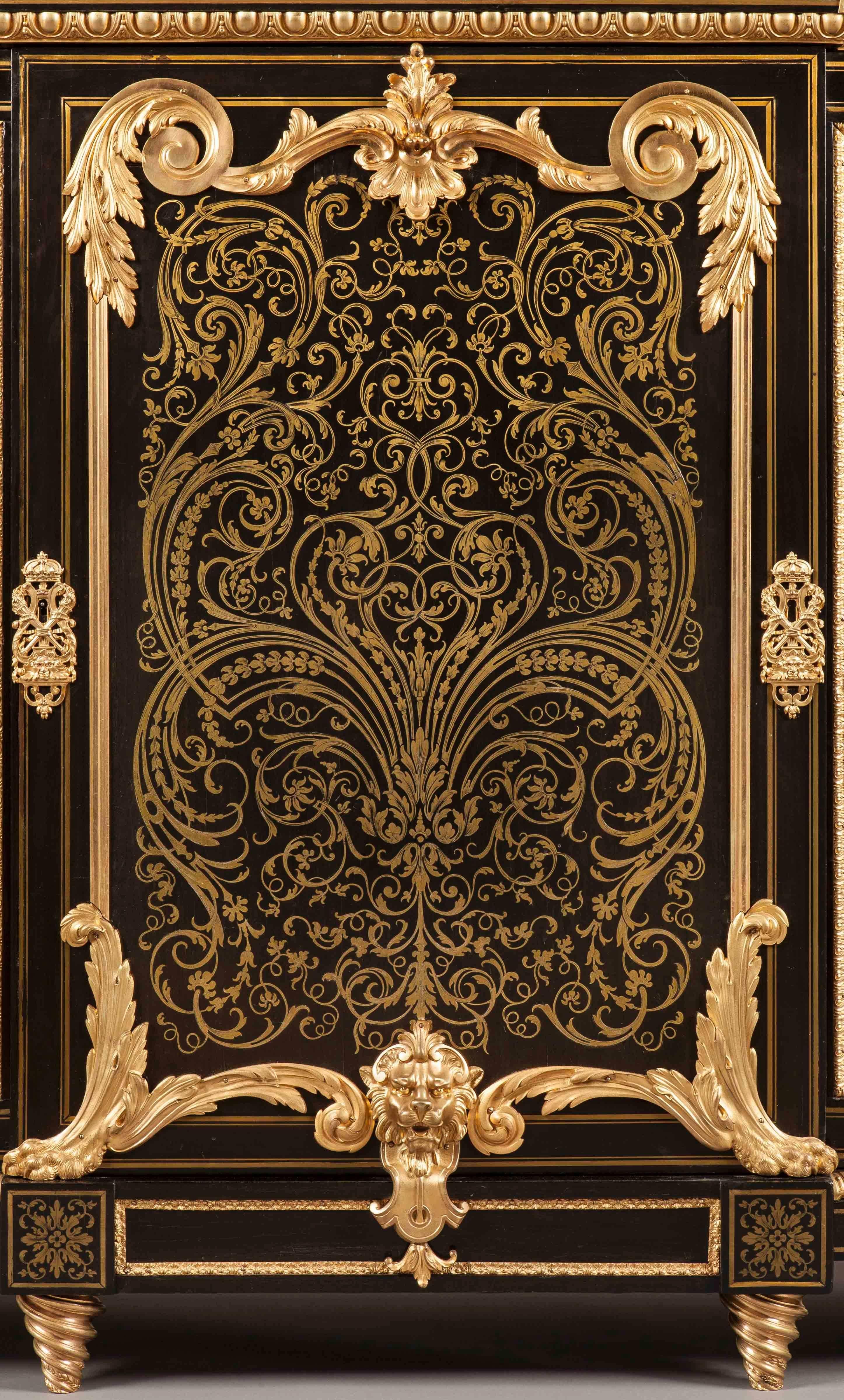 Constructed primarily in ebony and bronze, with cut-brass inlays; rising from tapering spiral toupie feet, the three lockable doors richly inlaid with brass arabesques, and having shaped gilt bronze mounts at the angles; the fields panel sides with