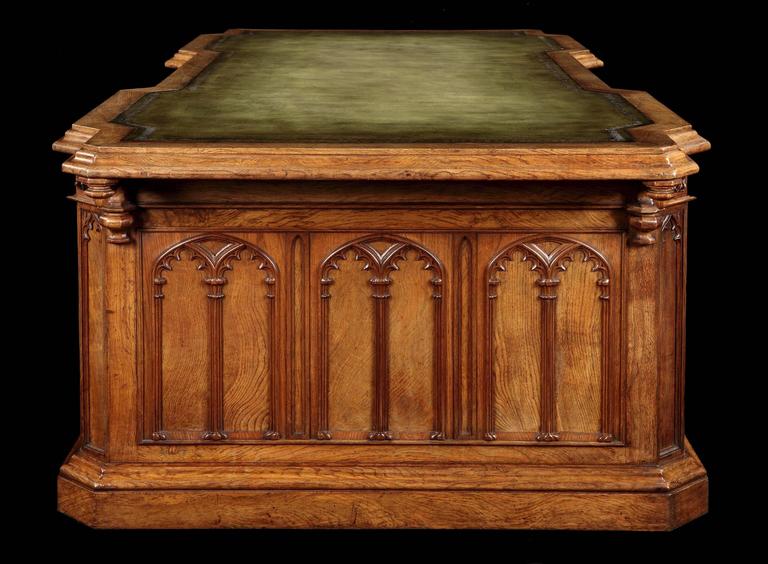 A magnificent monumental partner’s desk made in the Gothic style.

Constructed in a finely patinated oak rising from a plinth base, the canted corner pedestals having lockable blind doors, carved with lancet arcades, each enclosing four drawers