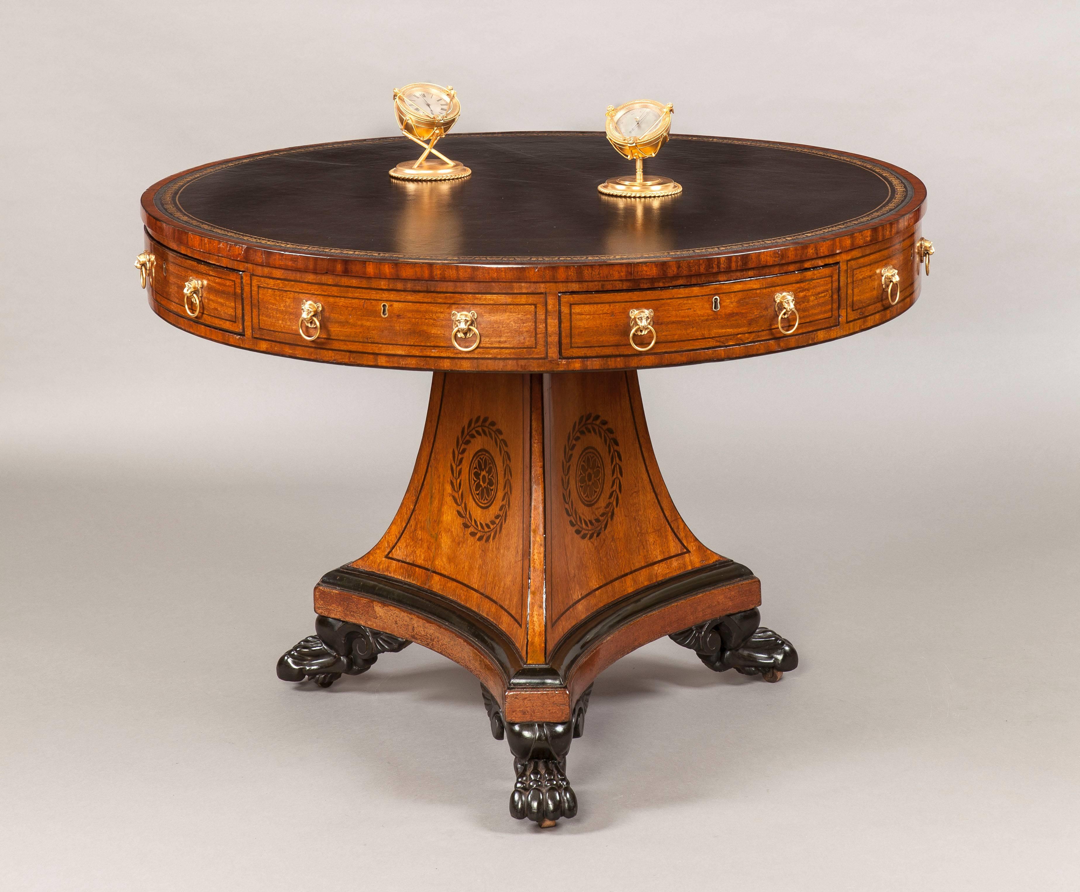 A Regency Period Drum Table

Constructed in mahogany, with holly inlays; the triangulated incurved pyramidical base, fitted with wooden castors, set within winged paw feet has inlaid laurel wreaths encircling paterae; the circular rotating top,