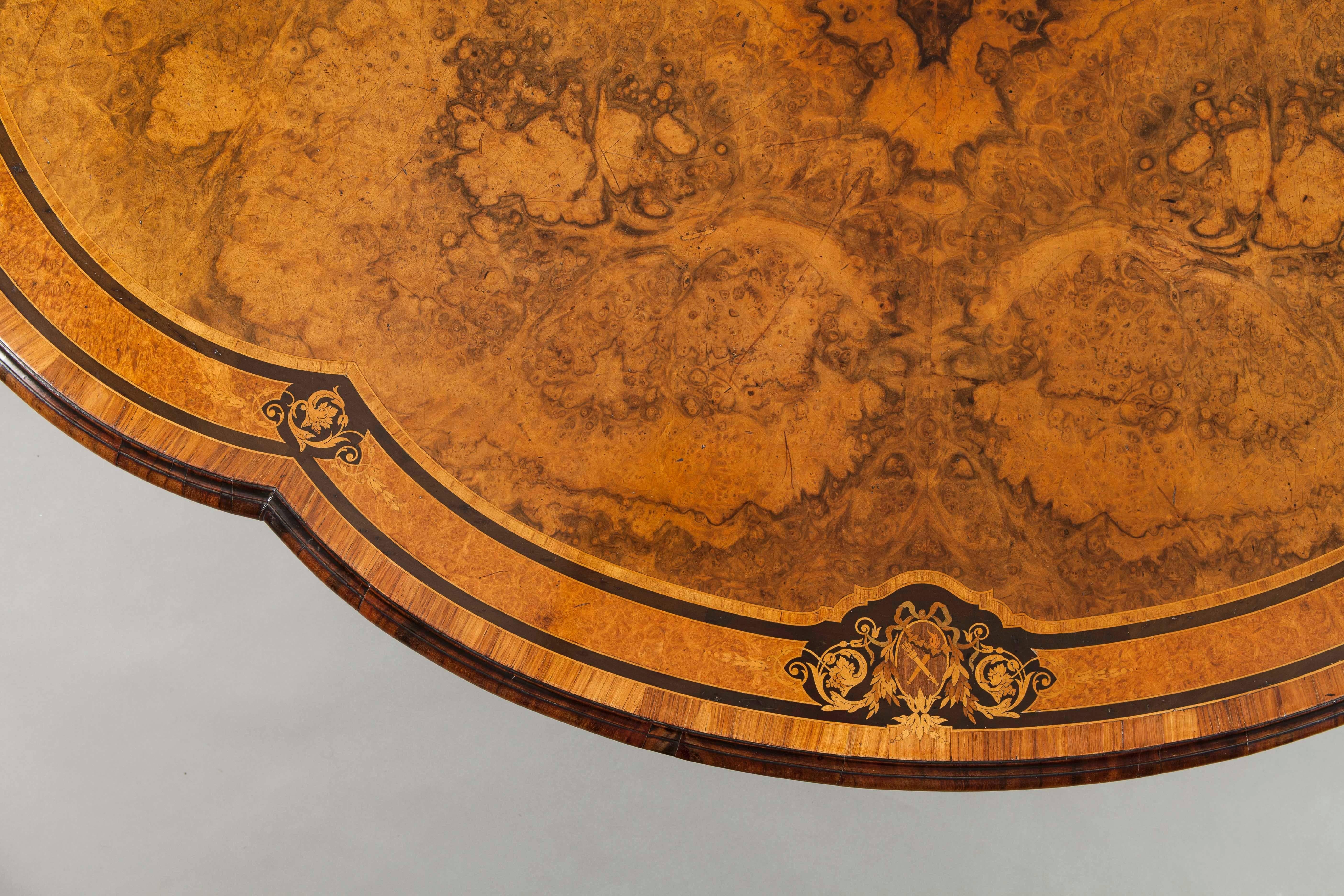 Table centrale de forme ancienne par Gillows

Construit en noyer circassien, avec des incrustations de bois spécimen, et des ornements en métal doré ; s'élevant d'une base quadripartite à pieds à roulettes, sculptée de feuillages ; une colonne