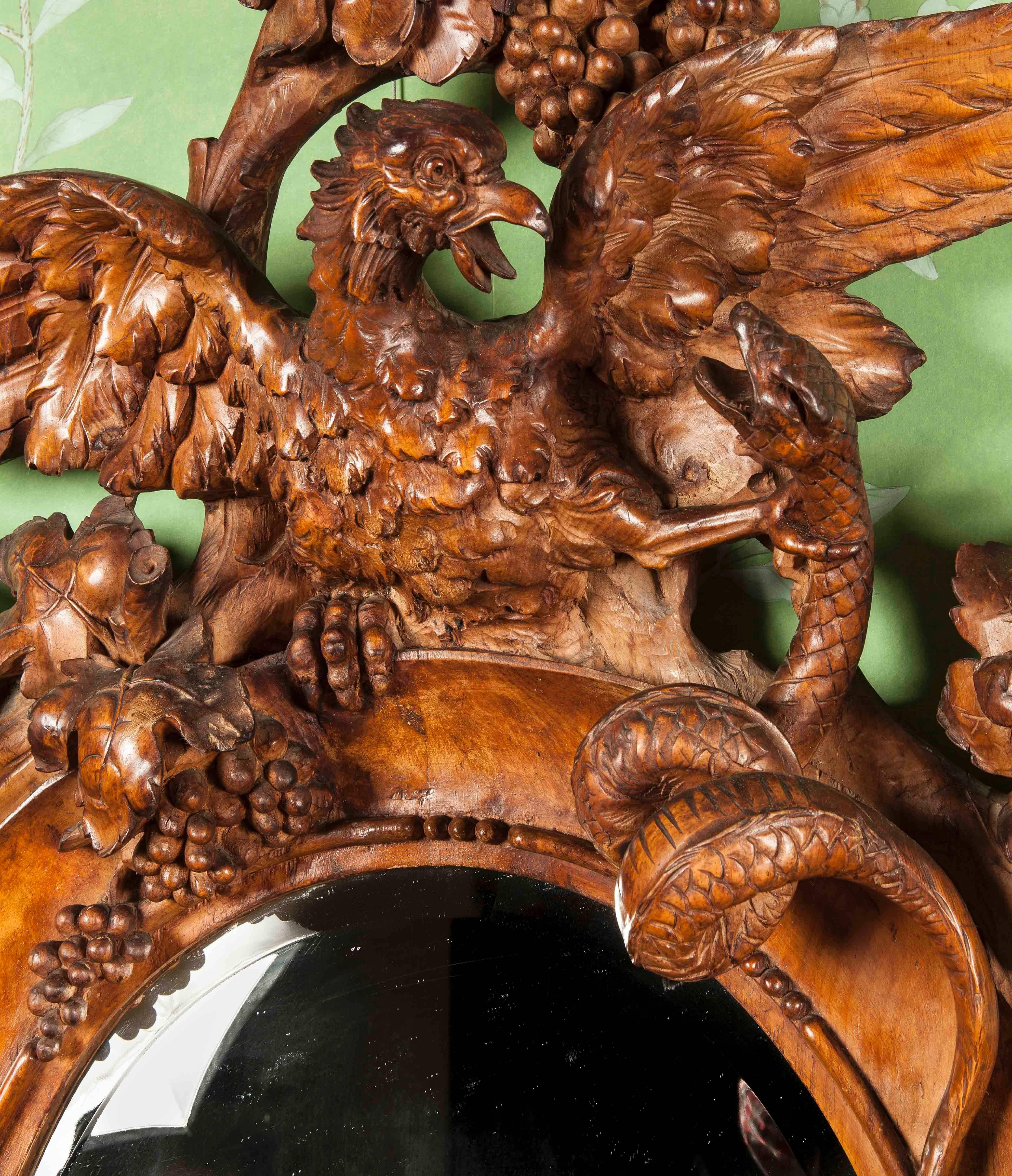 Constructed in walnut, richly and finely carved, rising from a serpentine base supported by shaped and scrolled feet, with an spread wing eagle, with one talon aloft, holding a shield shaped cartouche, over a grotesque mask, with an architectural