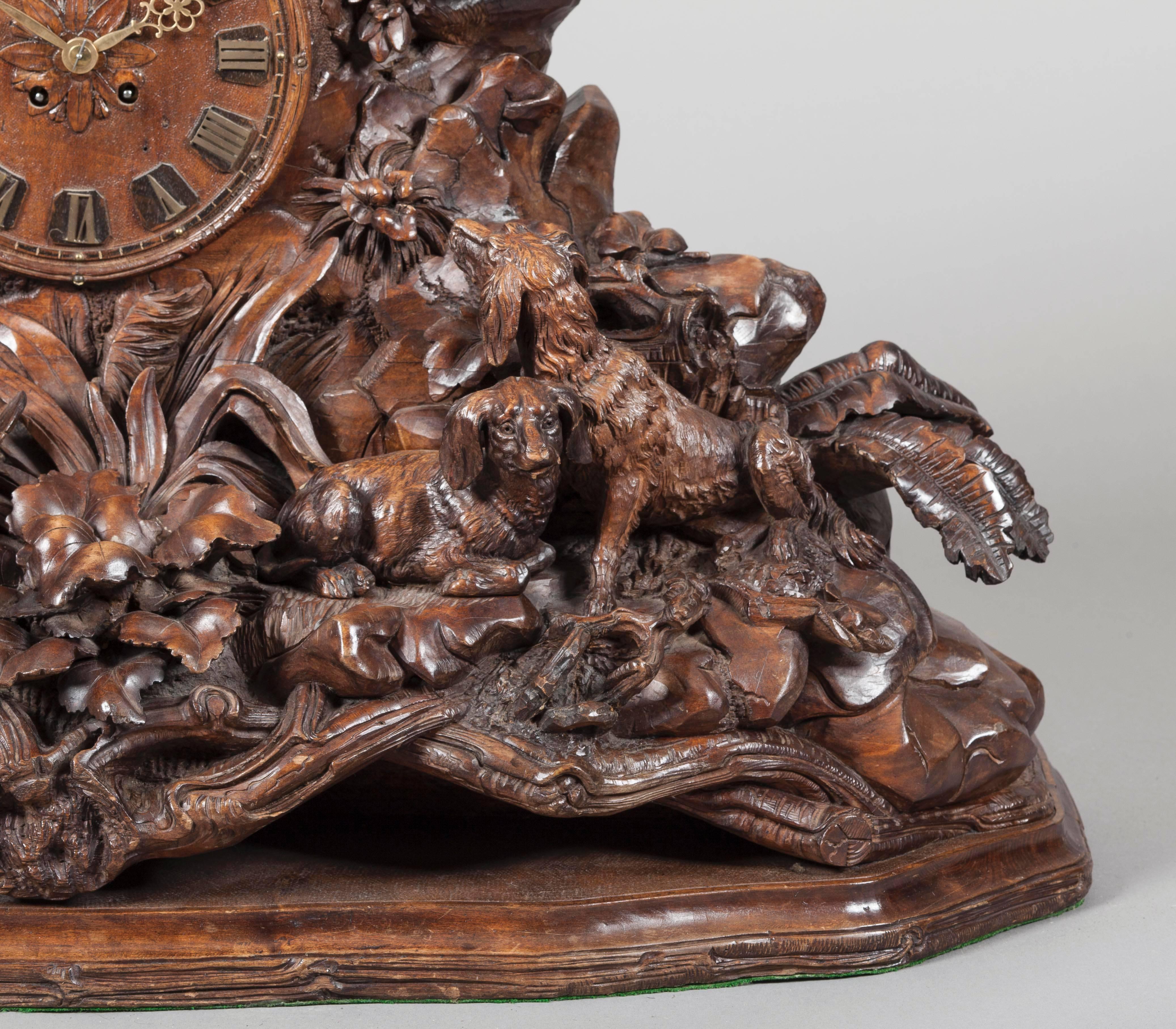 A Large Black Forest Mantle Clock

Constructed in carved linden wood, fitted with a two train eight day striking clock; mounted on a shaped serpentine base, with a moulded edge, the naturalistic ground of rockwork, tree branches, leafage and