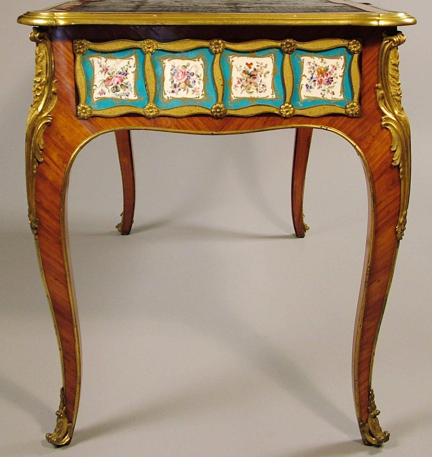 Un très beau bureau plat à la manière d'Edward Holmes Baldock.
D'après un modèle de C.C. Saunier.

De fabrication anglaise, dans le goût Louis XV, construit en bois de roi, avec une bande transversale en cœur de violette et orné de plaques de