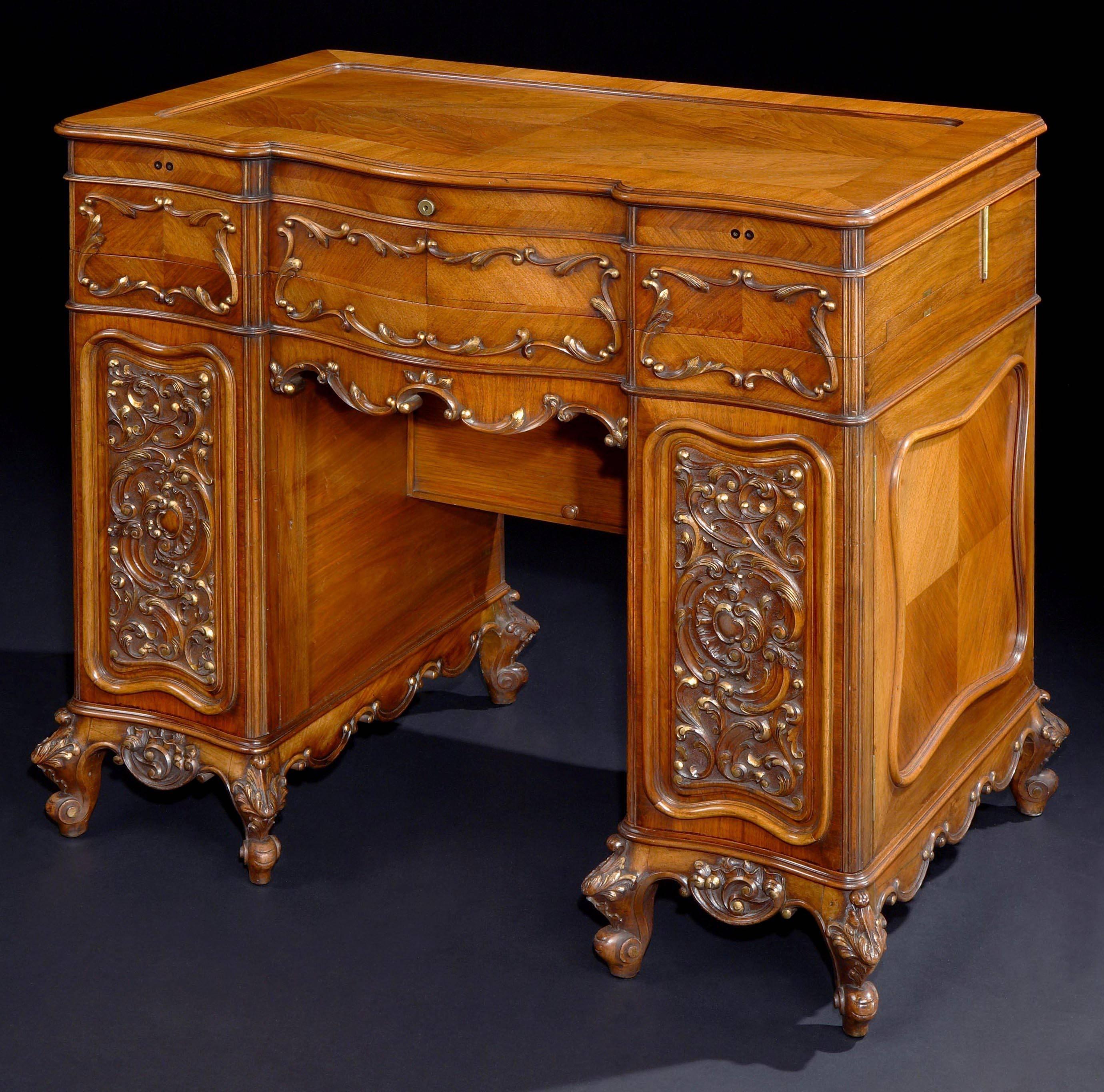 A ladies dressing table attributed to George Betjemann & Sons.

Constructed in quarter veneered walnut, rising from short cabriole feet, of kneehole pedestal form, with a shaped and moulded apron: the sides with asymmetrical fielded panel, the