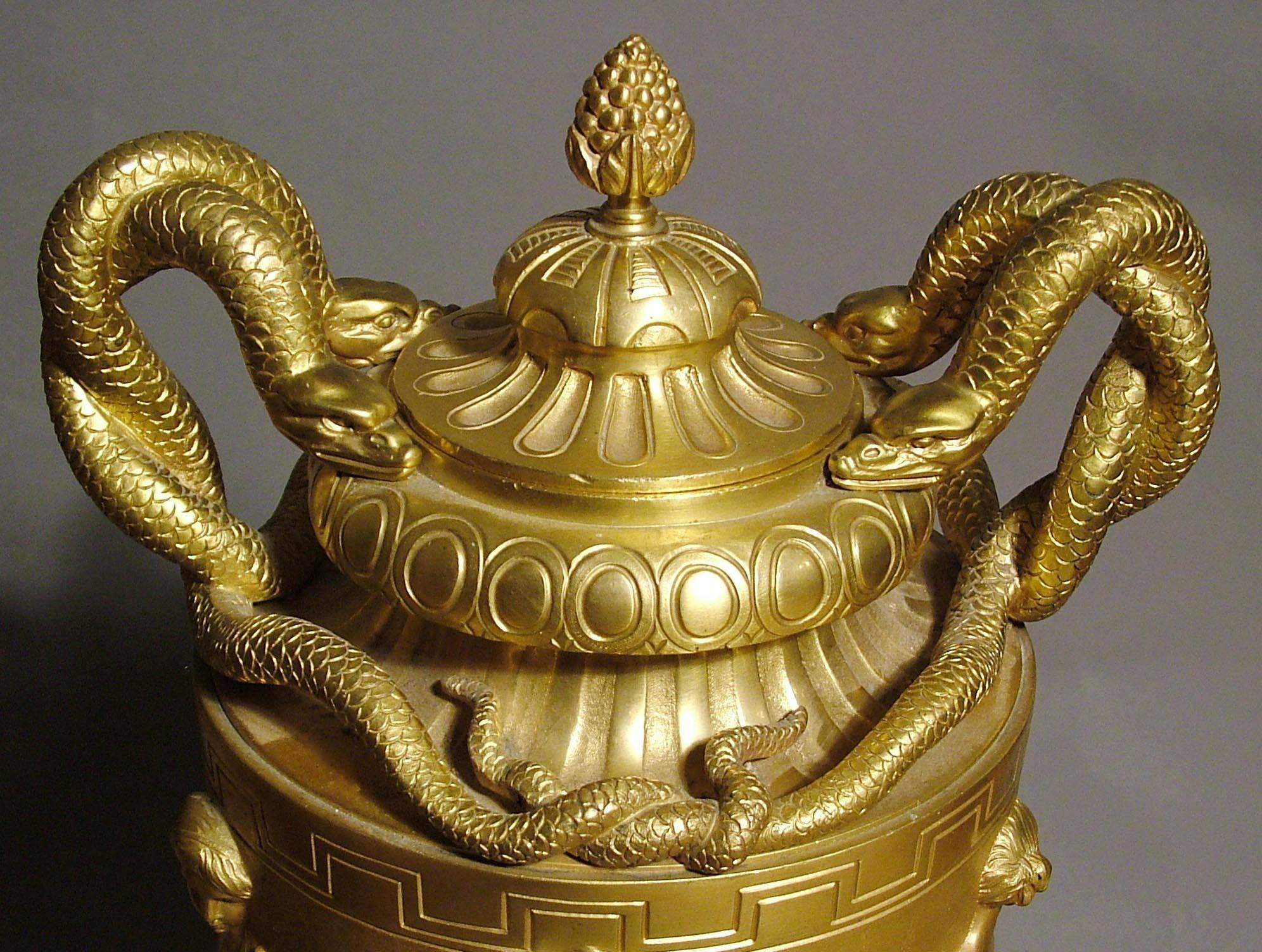 A fine pair of urns in the manner of Clodion.

Constructed in finely planished gilt bronze, rising from octagonal bases; of waisted baluster form, with entrelacs of laurel leaf bands; the dancing Grecian nymphs to the bodies of the vases known as