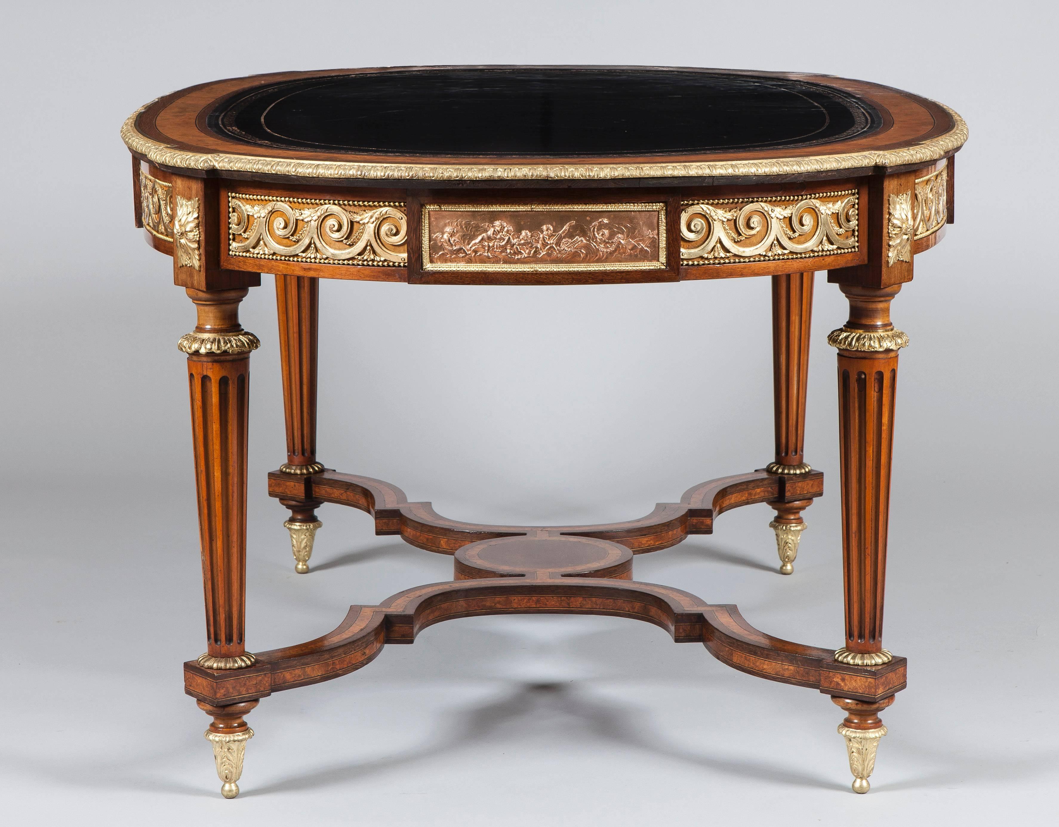 A Library Centre Table in the Louis XVI Manner

Constructed in amboyna, with purpleheart banding with gilt bronze mounts; of elliptical form, with gently everted angles; rising from circular bronze collared fluted legs capped with gilt bronze toupie