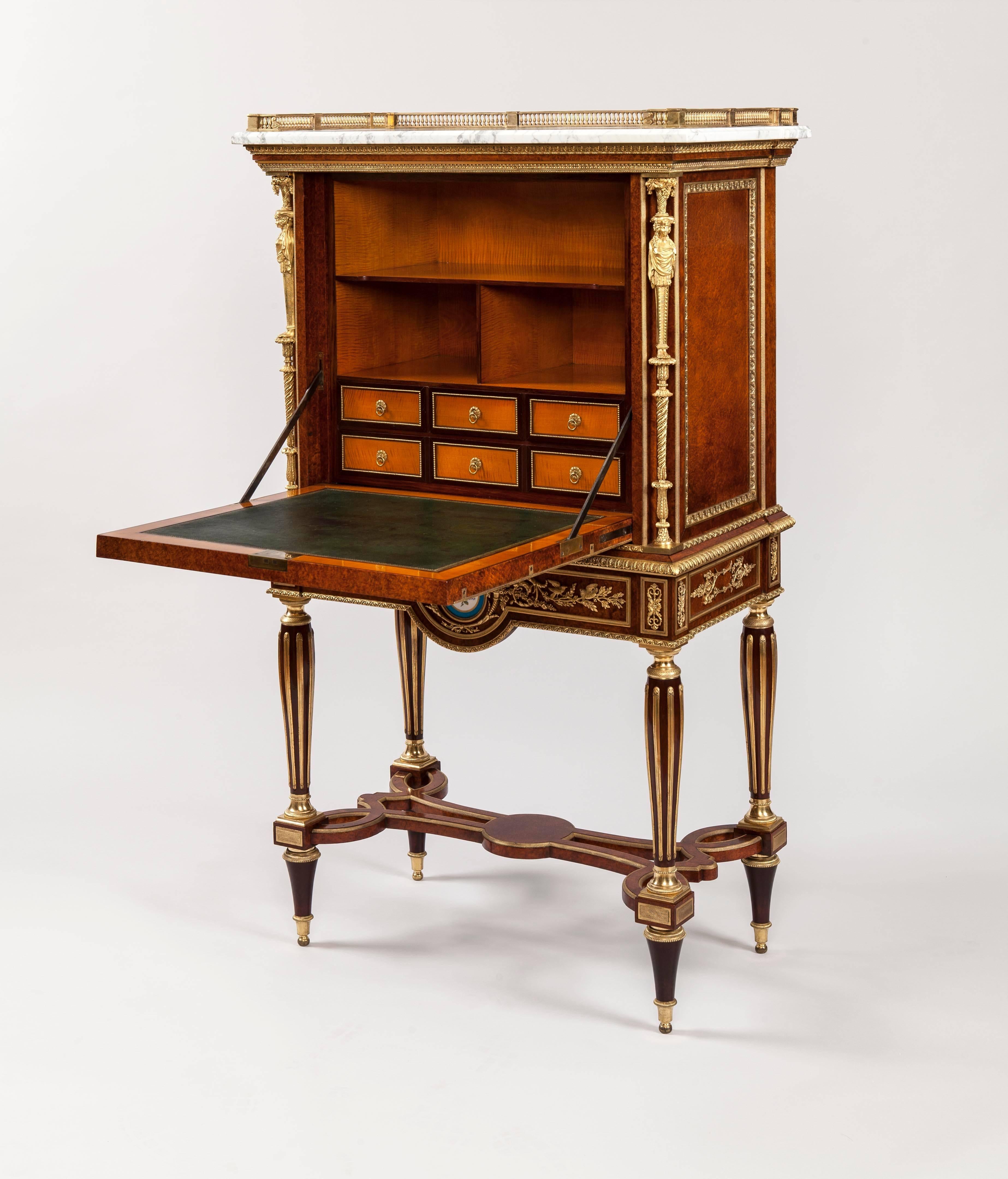 A fine Escritoire After a Design by Adam Weisweiler

Constructed in amboyna, dressed with blue and white floral ‘Sevres’ porcelain plaques and gold gilt bronze mounts; rising from tapering circular legs, inlaid with brass, having bronze bases and