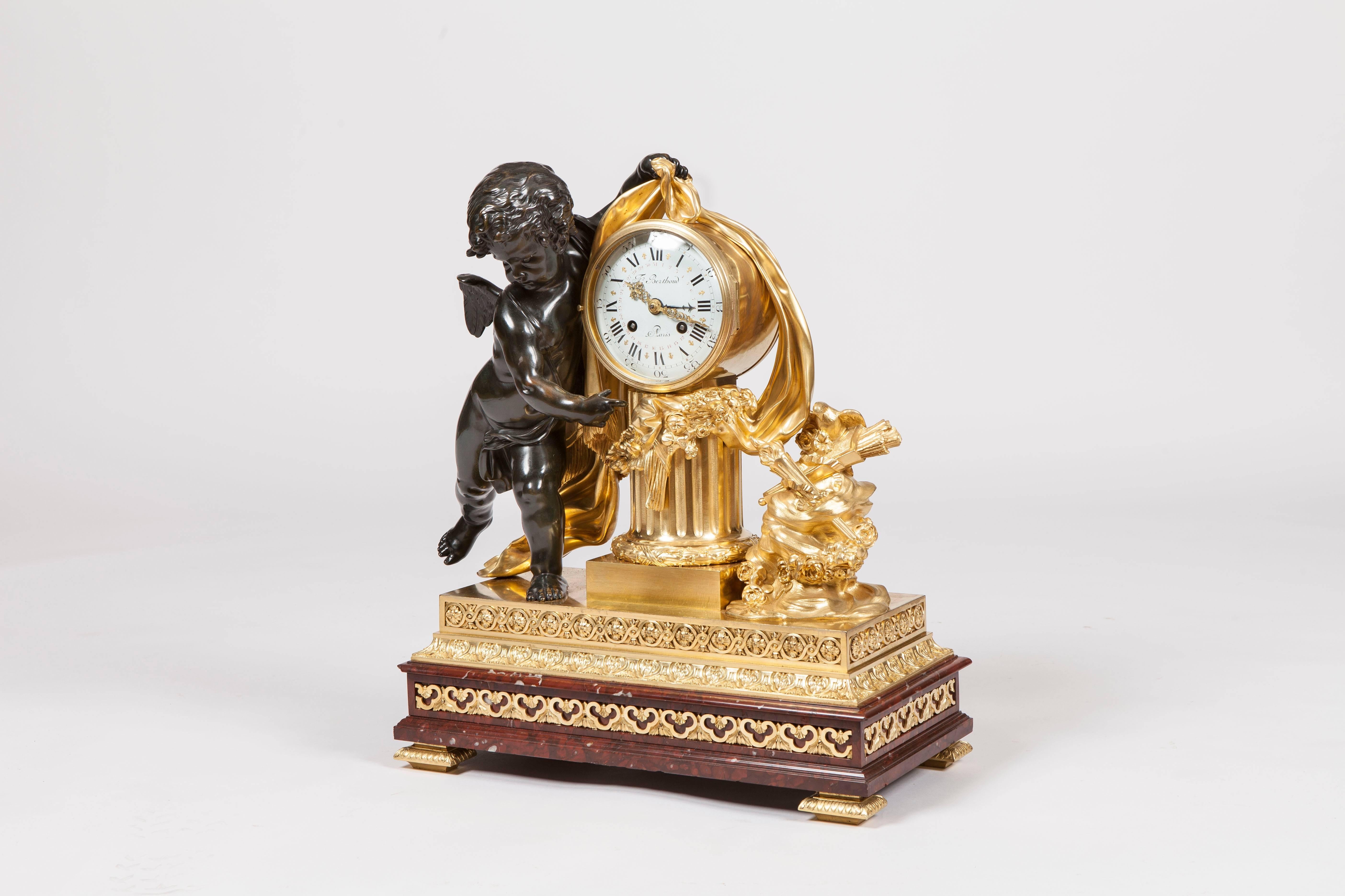 A fine garniture de cheminée firmly attributed to Henry Dasson

Constructed in both dark patinated bronze and gilt bronze, with Rouge Griotte marble; the clock case having a stepped platform base decorated with trefoil hearts and entrelacs, upon