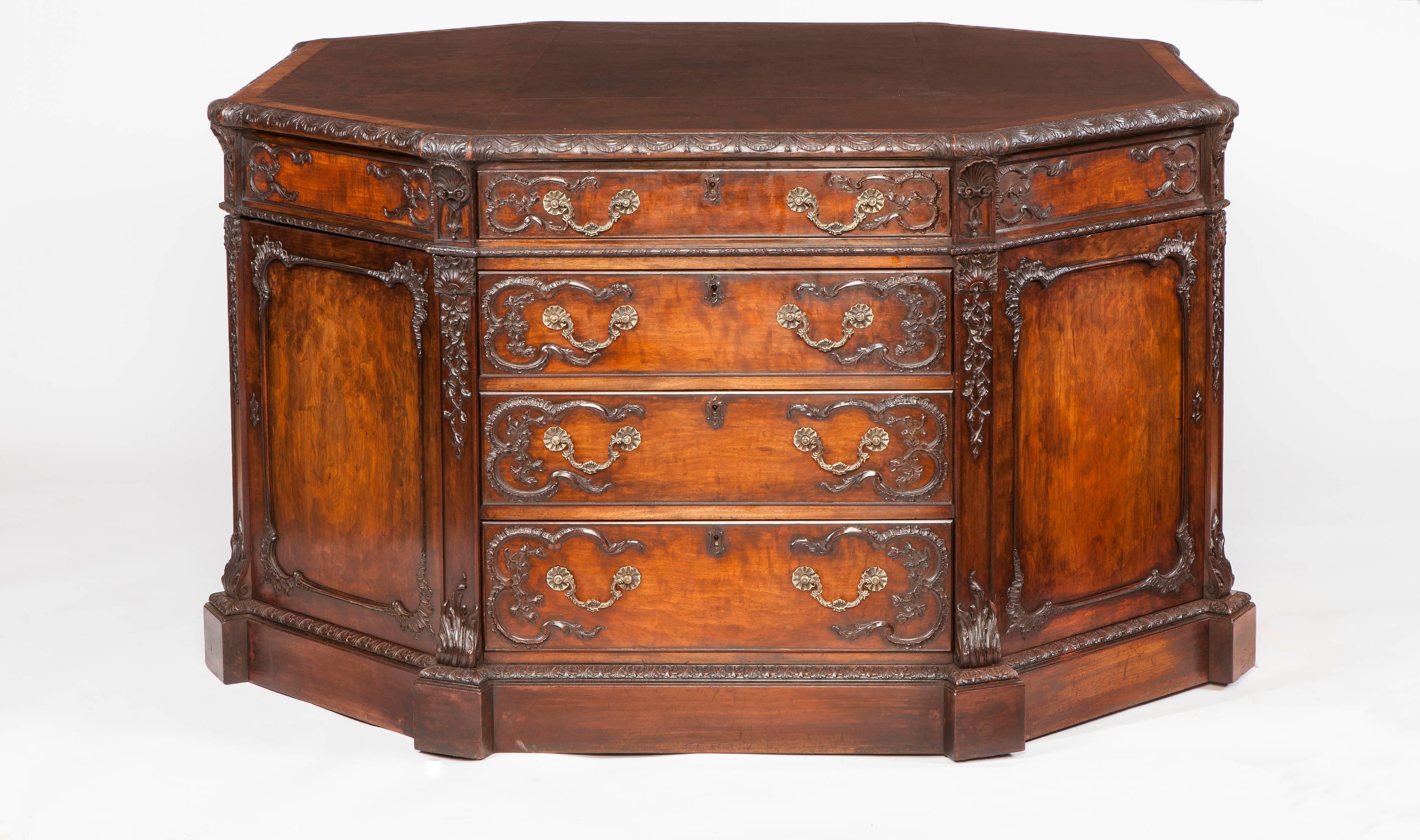 
A fine octagonal library desk stamped by H. Samuel of London

Constructed in a well figured mahogany, adorned with applique rocaille scroll work rising from foliate carved and shaped plinth inset feet, the pedestals separated by reeded stiles