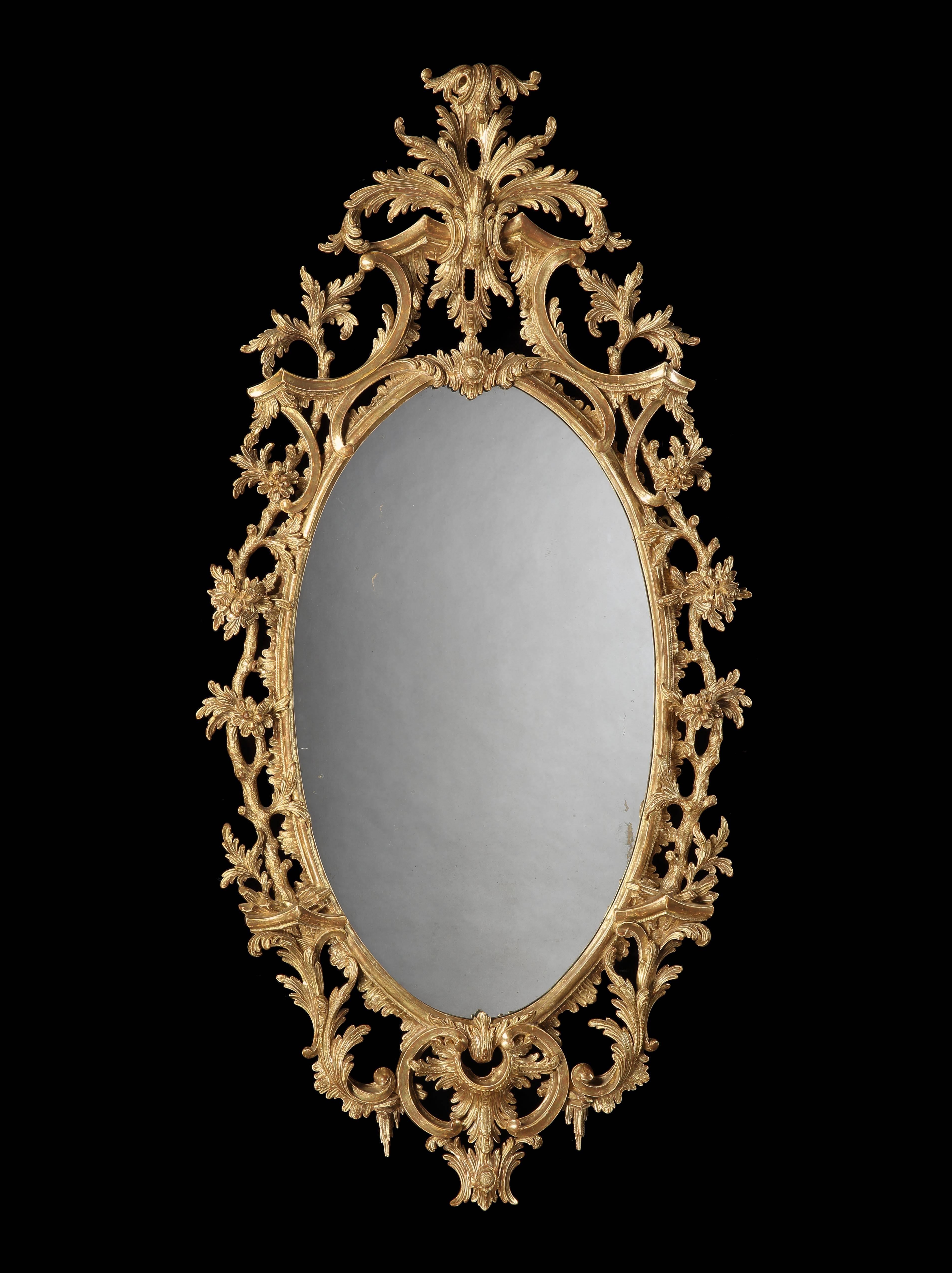 The elliptical mirror plates enclosed by gesso and gold giltwood frames, exuberantly carved with scrolling acanthi, foliates and scrollwork in the Rococo manner, the surmounts having cabochons issuing acanthus spray crests,
circa 1880

Graham