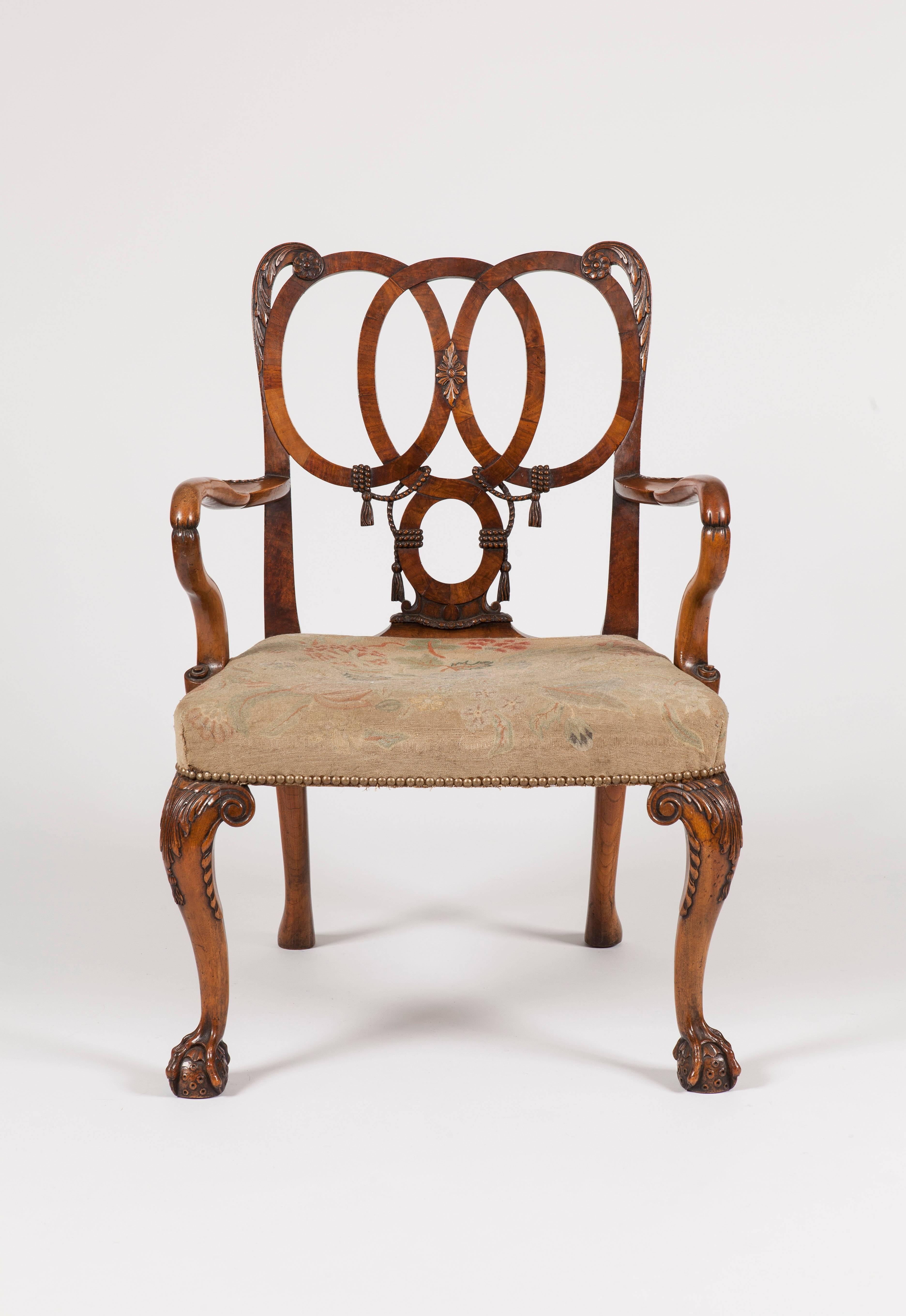 An armchair in the style of the George II
for Charles Tozer of Brook Street London

Constructed in walnut; rising from ball and claw footed cabriole legs, with carved scrolling at the shoulders, issuing ‘shepherd's crook’ arms, with dished