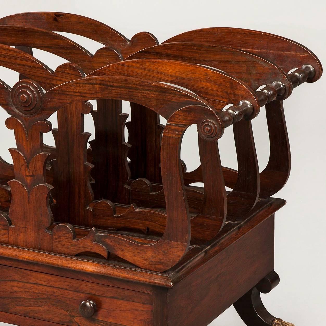 Constructed in goncalo alves, with four divisions, the top rail of arc-en arbalette form, with turned dividers; the central support in the form of a stylised palm tree trunk; a single mahogany lined drawer below and rising on swept legs terminating