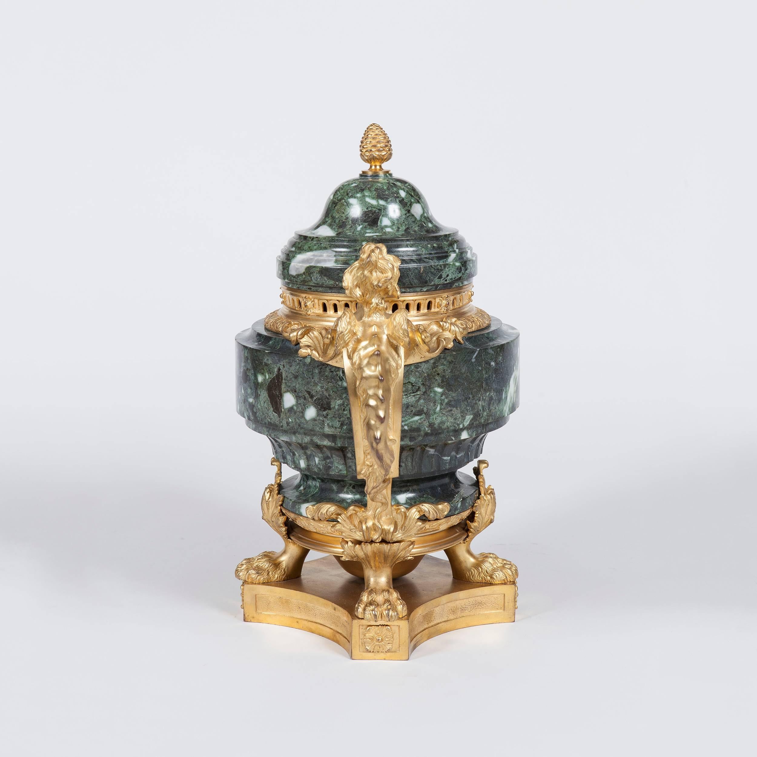 A fine pair of marble vases in the Régence manner

Constructed utilizing a strikingly marked Grecian green marble, dressed with ormolu mounts; the bases of incurved square form, with flower heads at the angles, and rectangular panels with piqure