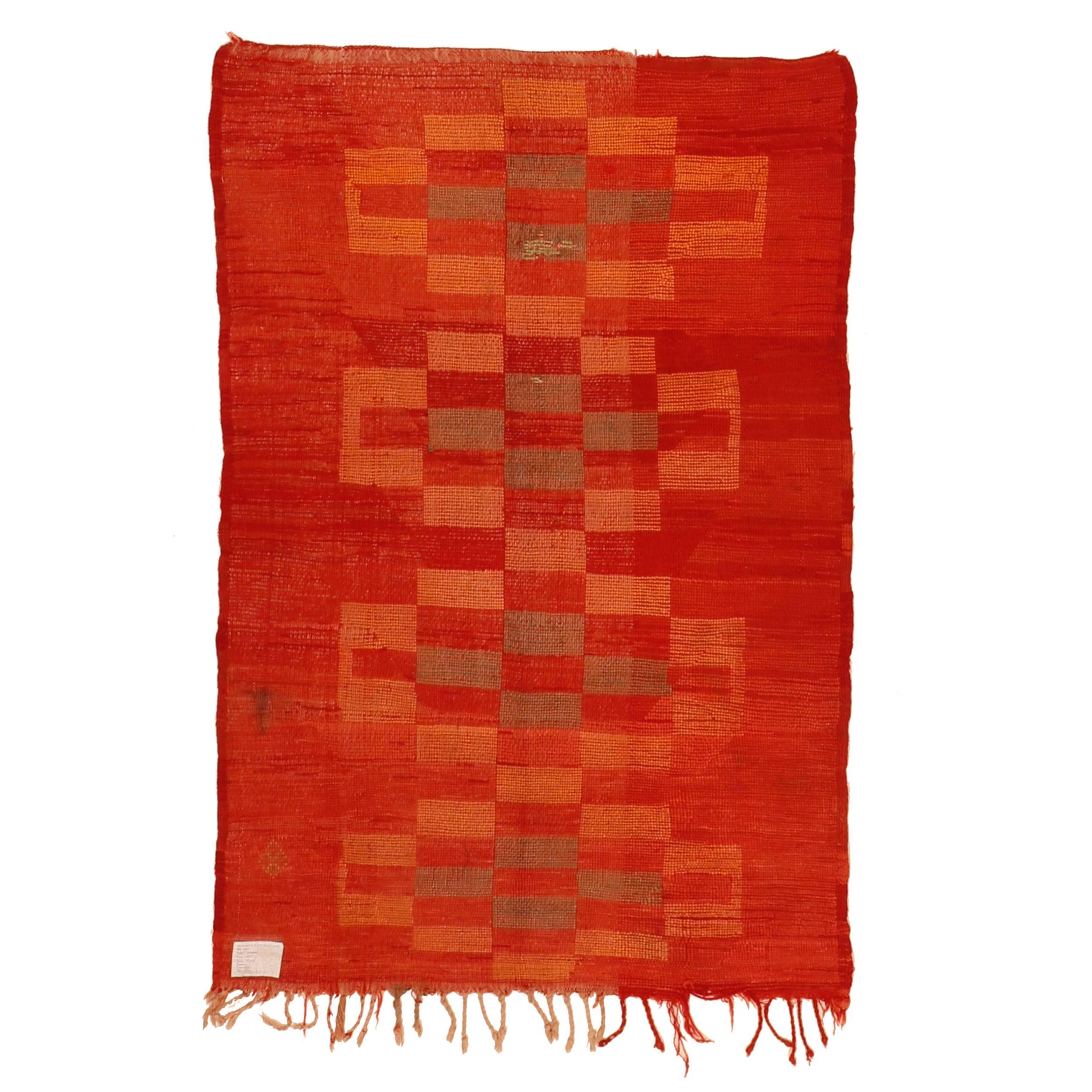 A delightful Berber rug originating from the Berber village of Mrirt decorated by four conjoined elements consisting of the chequerboard motif. The design appears as if it was carved in the orange-red background, where the weaver ingeniously