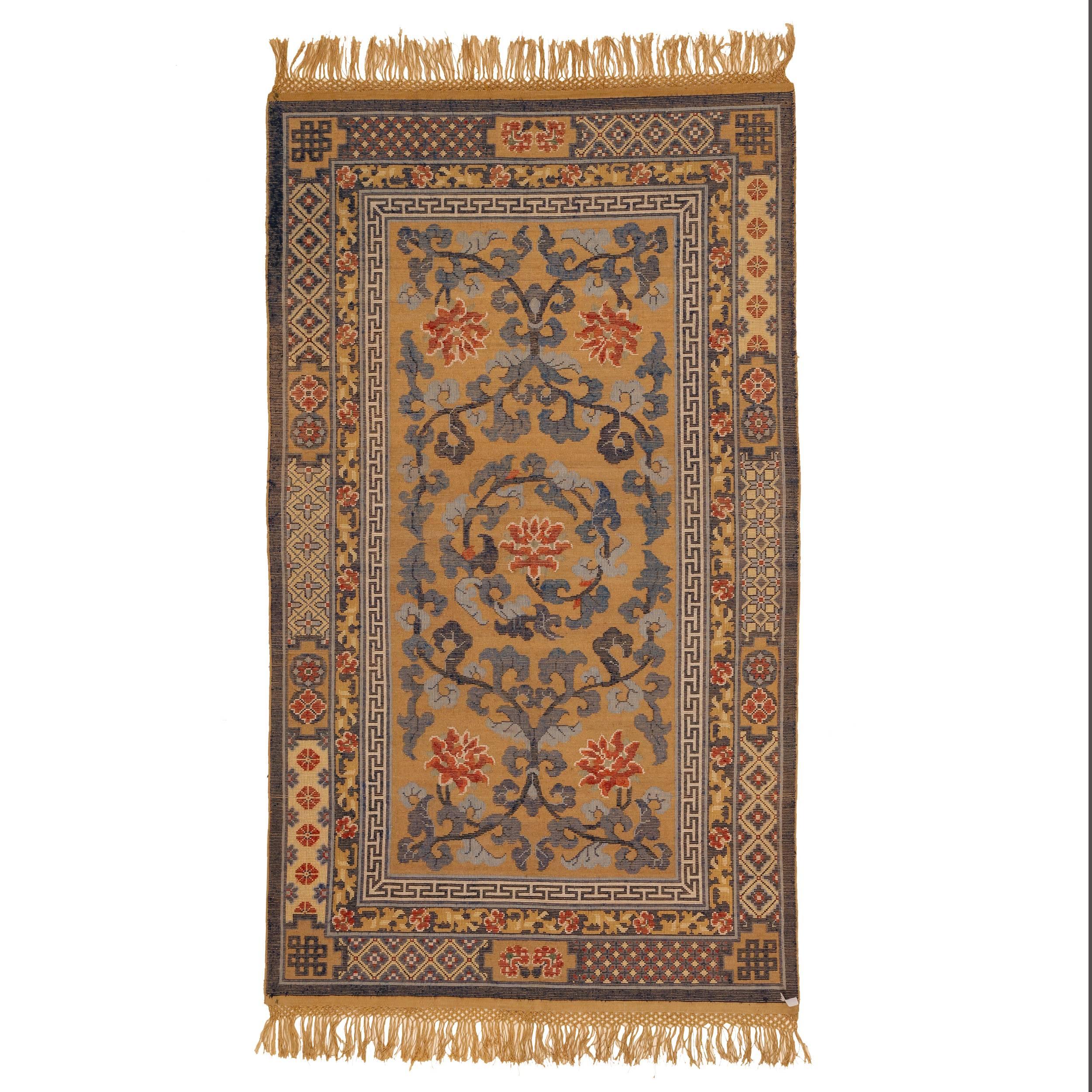 A very finely woven rug in silk and metal thread distinguished by a pattern of swirling leafy stems from which sprout large lotus flowers (symbols of purity. The silk pile is embossed, meaning that its pile is raised relative to the metallic-thread