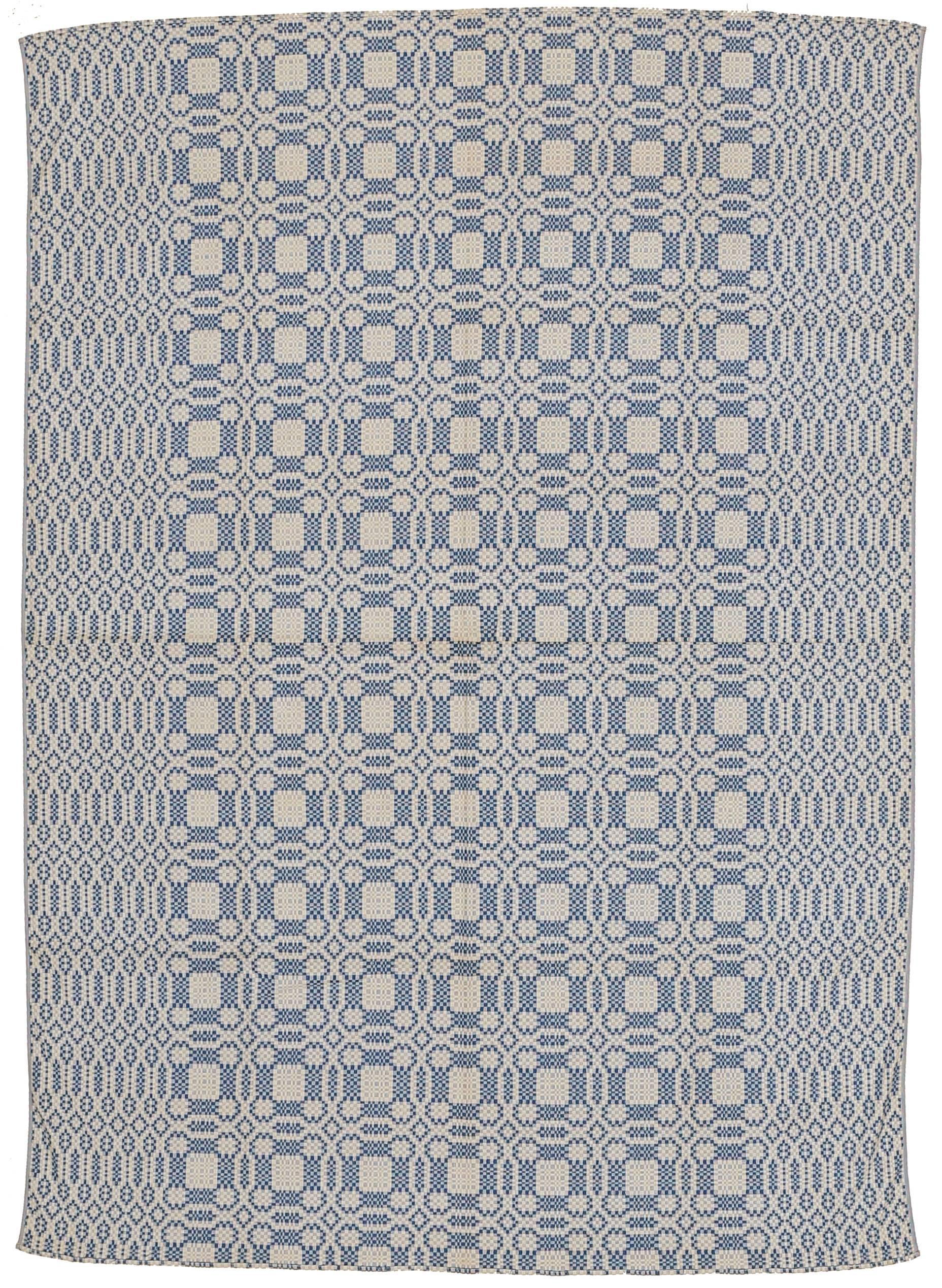 A fine antique North American reversible cotton coverlet, distinguished by a repeat pattern of overlapping roundels containing geometric motifs in medium-light blue on an ivory background. The geometric border consists of stacked rows of stylised