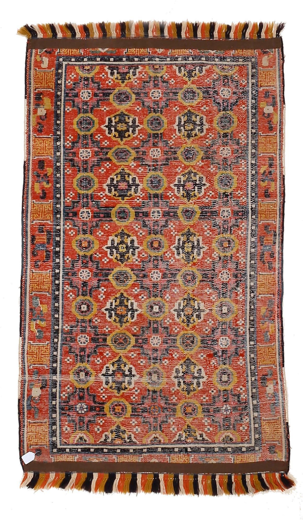 A rare and unusual red ground Chinese rug decorated by an infinite repeat pattern composed of a network of geometric devices derived from silk brocades of the Ming period. Examples of this type were most probably commissioned for monastic use, as