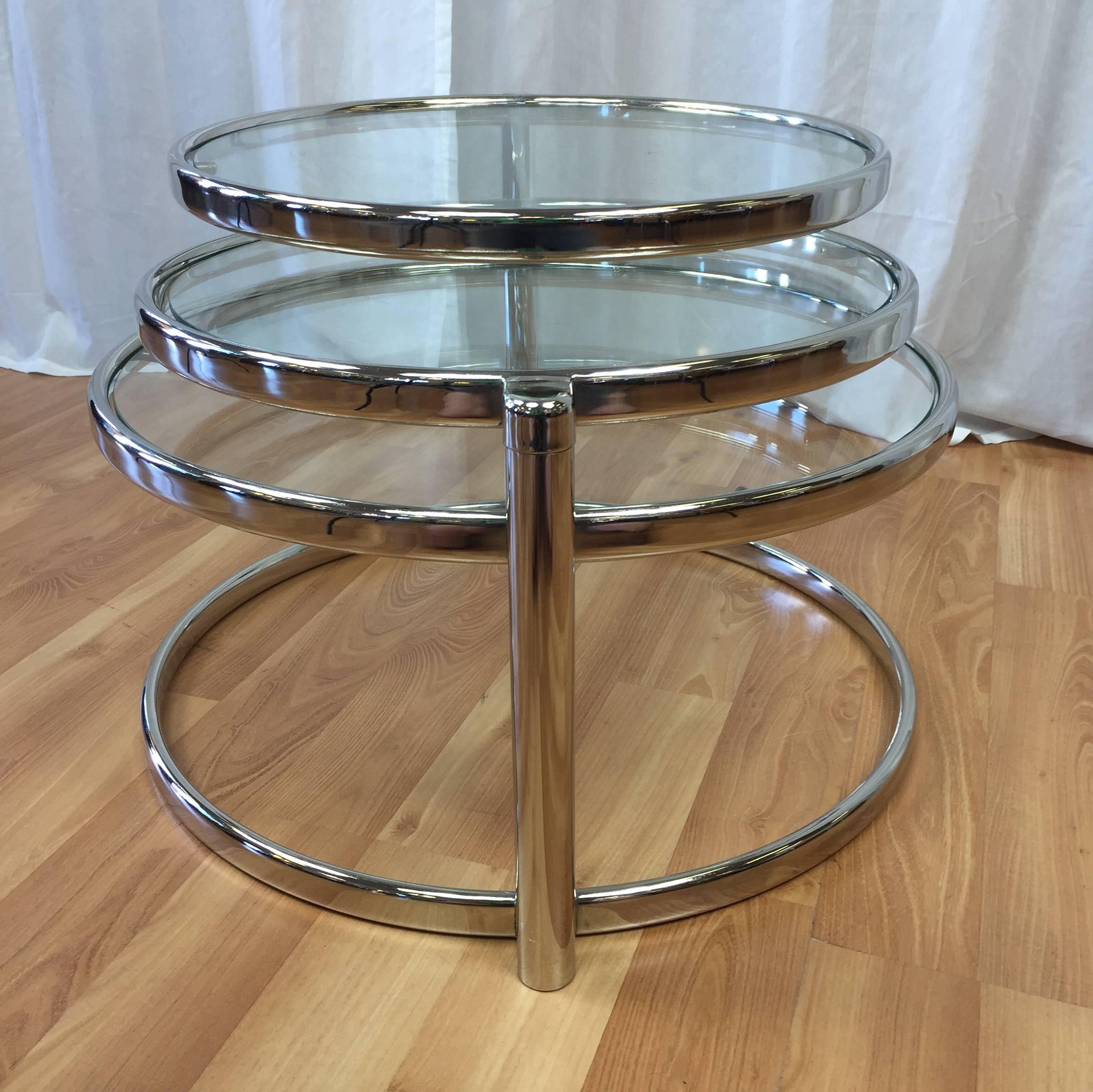 A polished nickel and glass swiveling three-tier table in the manner of Milo Baughman.

Features four stacked rings, which encompass a sturdy base, a glass-topped fixed tier and two glass-topped swiveling tiers that allow this sleek piece to
