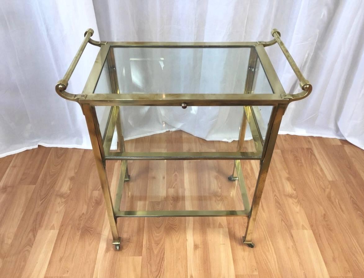 An unusual Hollywood Regency brass and glass cocktail cart or server with a vitrine top.

Clever design incorporates a jewel box-like top that can be accessed by four drop down doors. Perfect for dust-free storage of your finest barware, or for