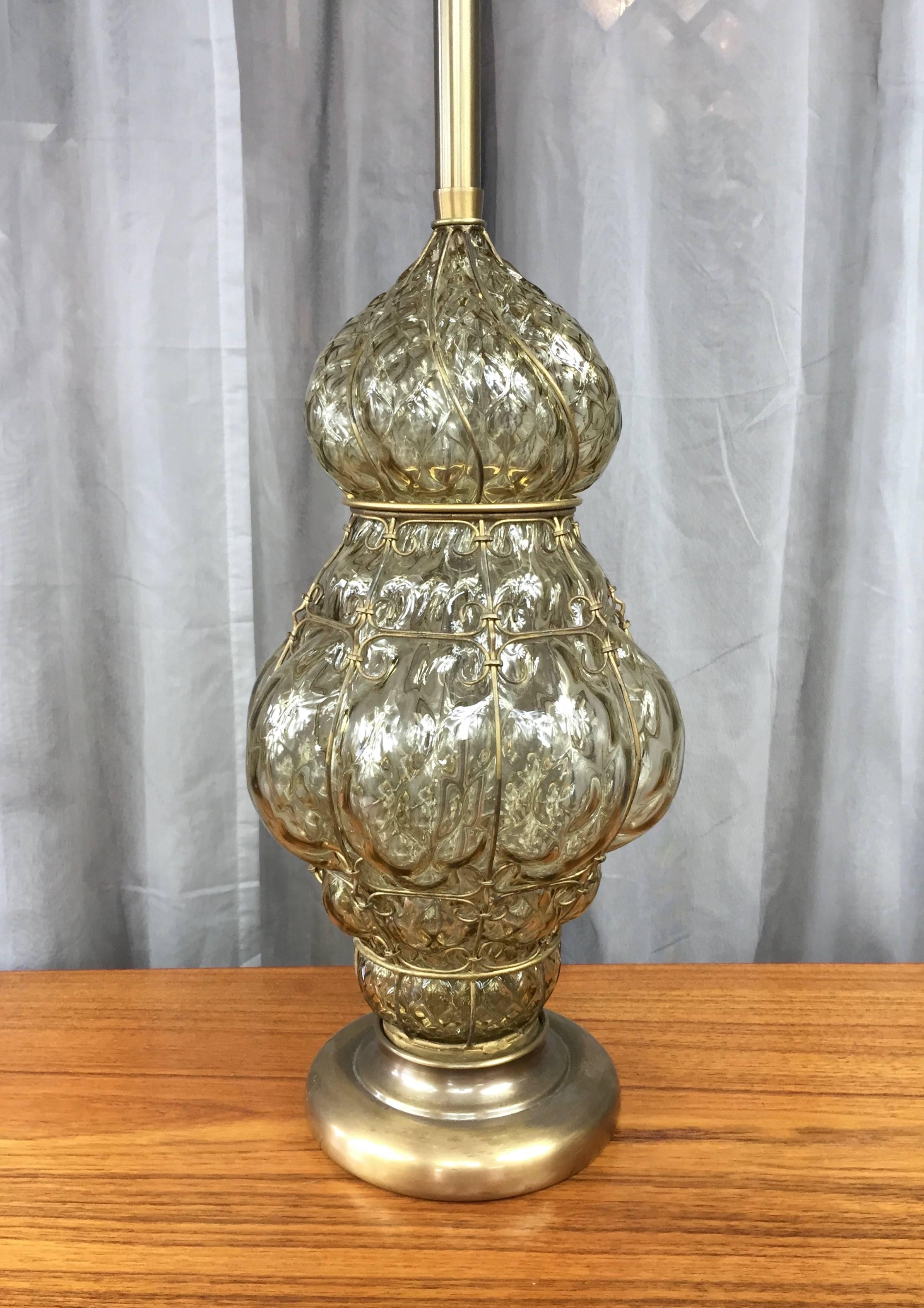 An extra-large optic effect Murano glass table lamp with brass base and stem, and brass-colored wire cage and finial.

Glass is cool-hued champagne in color, and has a jewel-like appearance due to a dazzling diamond pillow pattern throughout.
