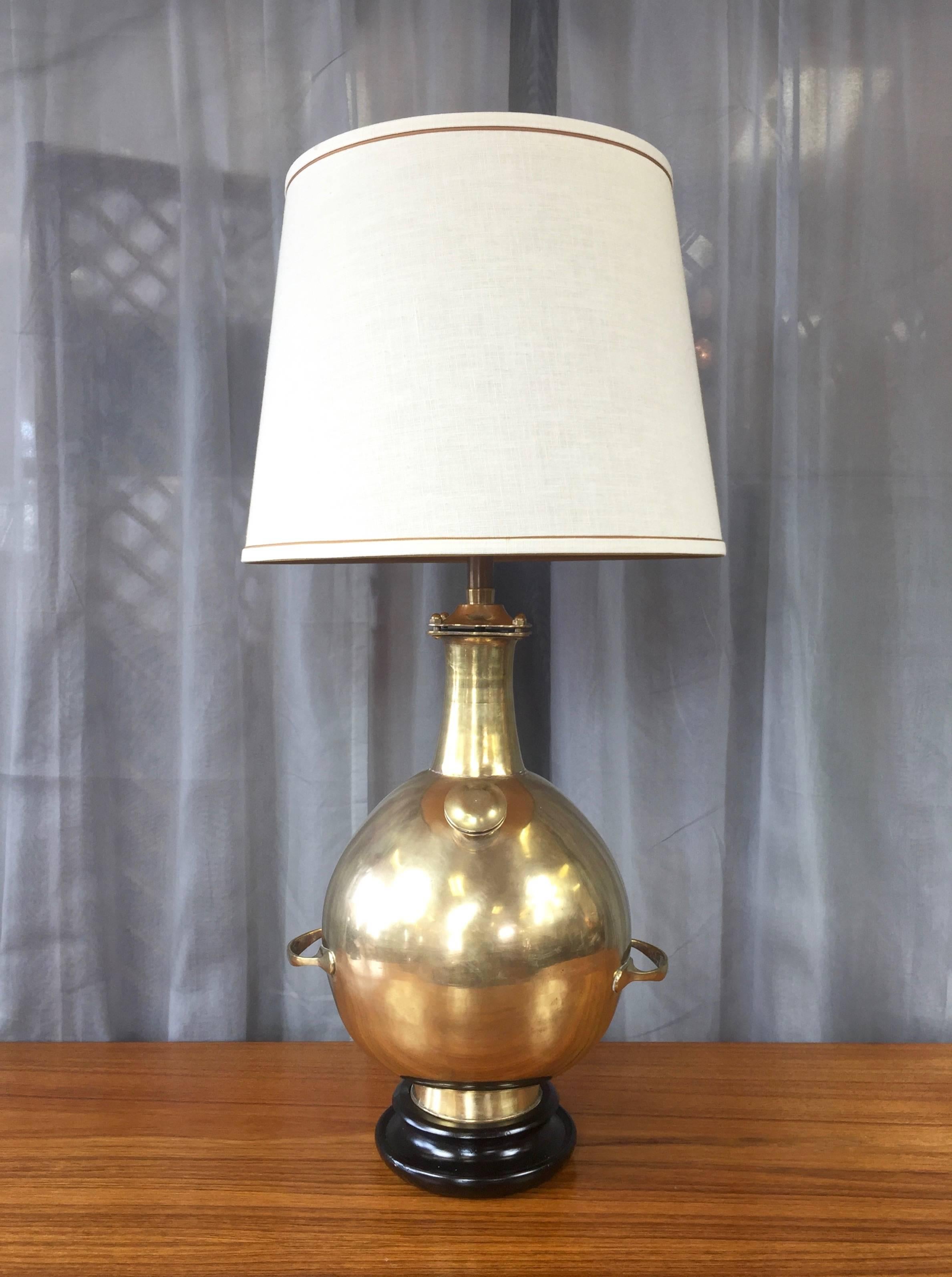 An impressively sized and uncommon Marbro brass table lamp on lacquered wood base.

Substantial, heavy, and gleaming brass body features a number of interesting Machine Age design details that evoke an antique diving bell or pressure cooker.