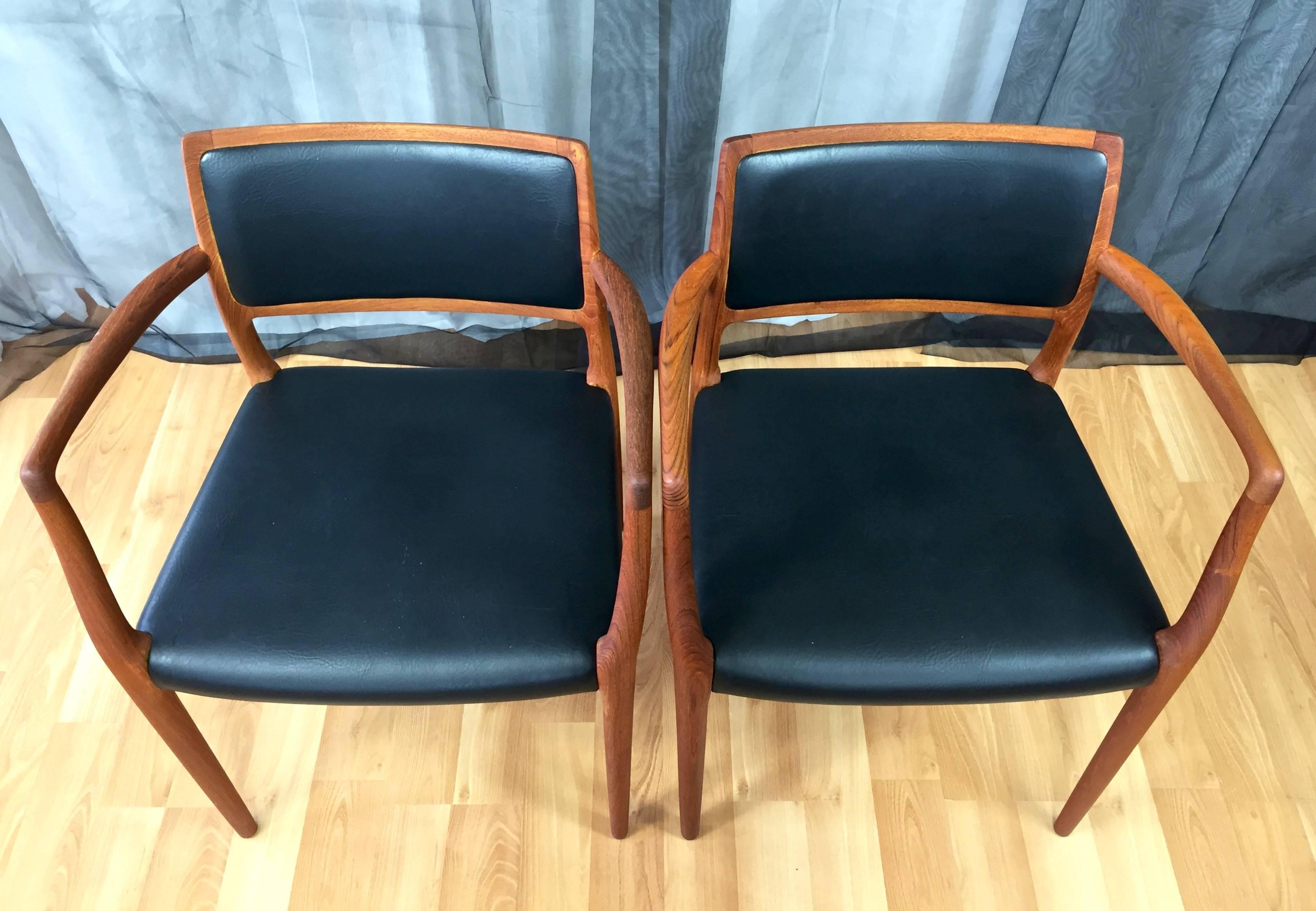 A pair of Danish Modern Niels Møller Model 65 teak and leather dining chairs with arms for J.L. Møllers Møbelfabrik.

Hand-shaped solid teak frame exemplifies Møller’s signature sculptural approach. Very comfortable ample seat and inset back