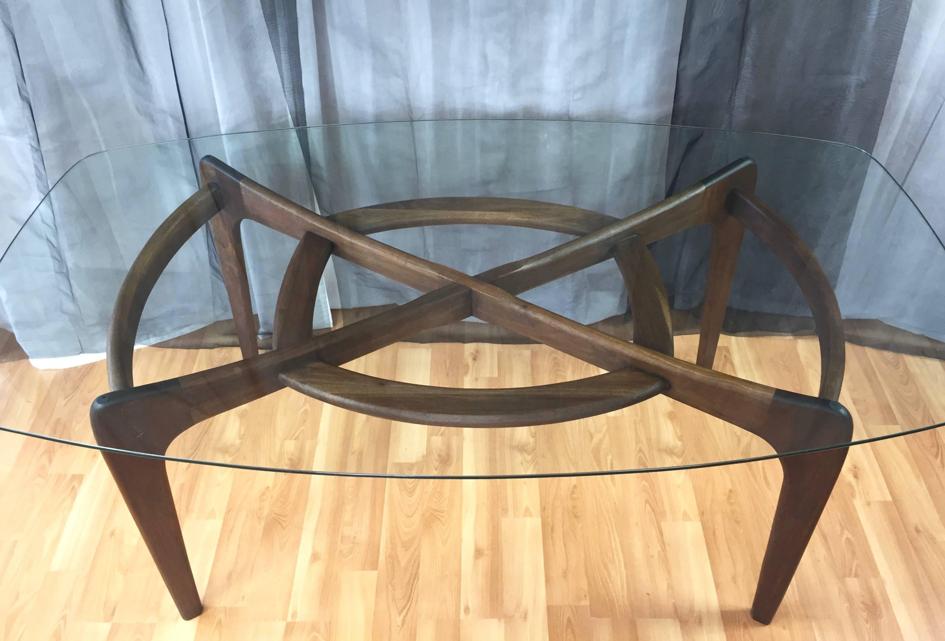 A Mid-Century Modern solid oak dining table with glass top by Adrian Pearsall for Craft Associates.

Handsome base exhibits excellent craftsmanship in its sculptural forms and intersecting construction, which is a signature of Pearsall’s iconic