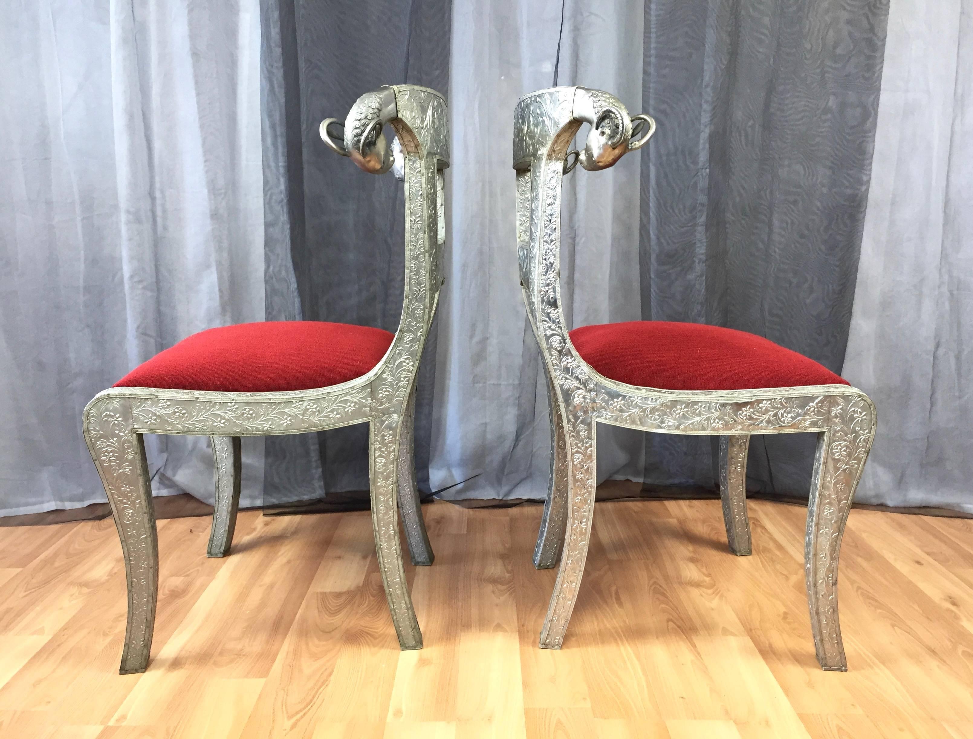 An enchanting pair of antique Anglo-Indian or Anglo-Raj metal-clad wedding dowry chairs with ram’s head finials.

Wood frame completely covered in incredibly intricate handcrafted and gleaming tin repoussé. Features a floral and love bird motif