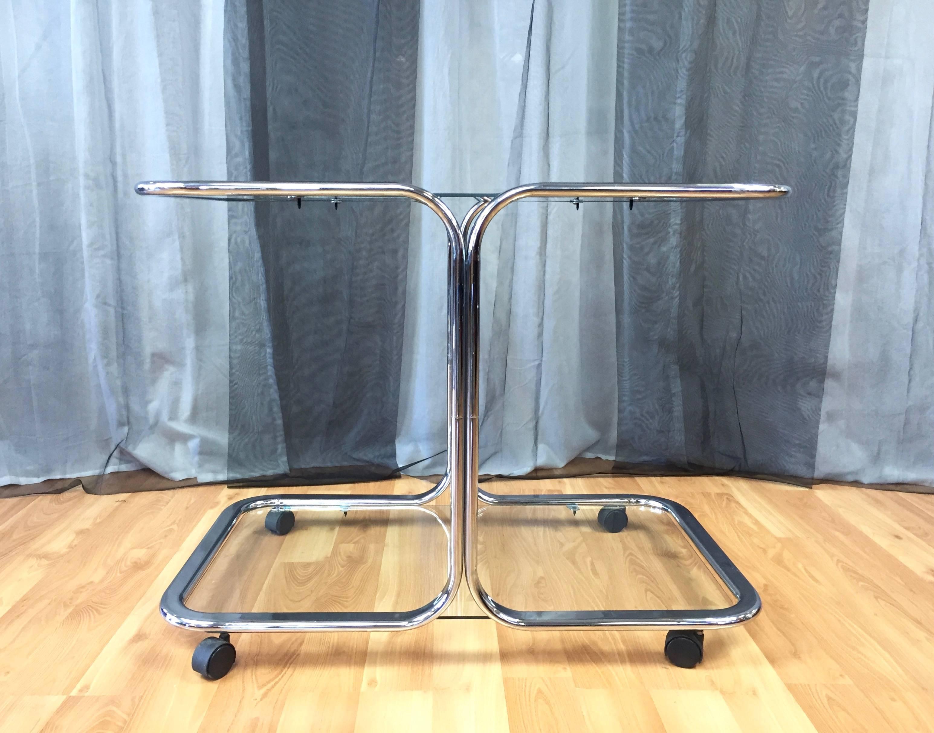 An exceptionally sleek and Minimalist two-tier chrome and glass bar or serving cart in the manner of Milo Baughman and Design Institute America.

Continuous round-edge flat bar chrome halves mirror each other, and support two expansive glass