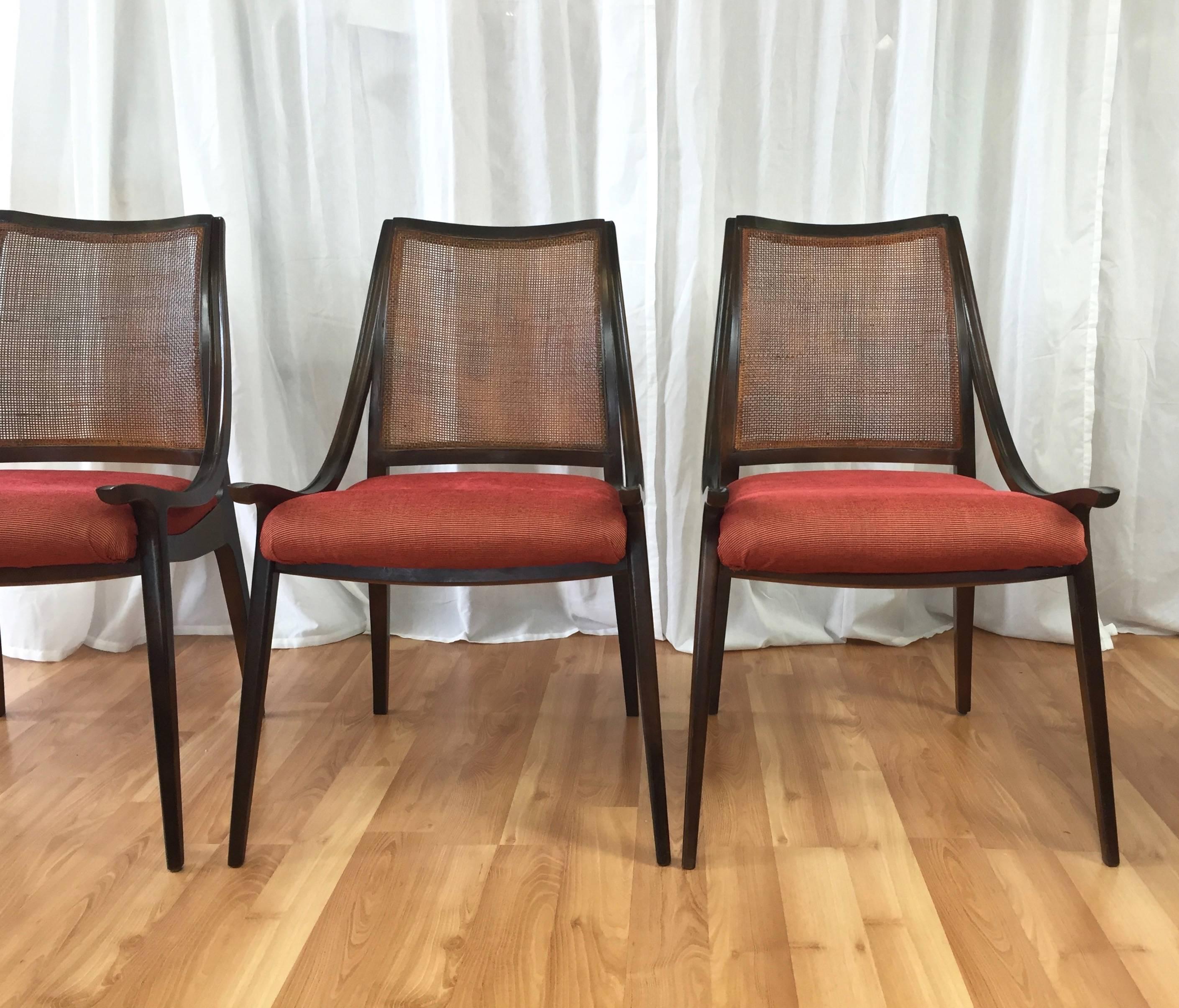 A four-piece set of uncommon mid-century walnut dining chairs with woven cane backs and upholstered seats by Richard Thompson for Glenn of California.

Curvaceous back and low-profile arms create an unusually striking silhouette. Walnut frame is