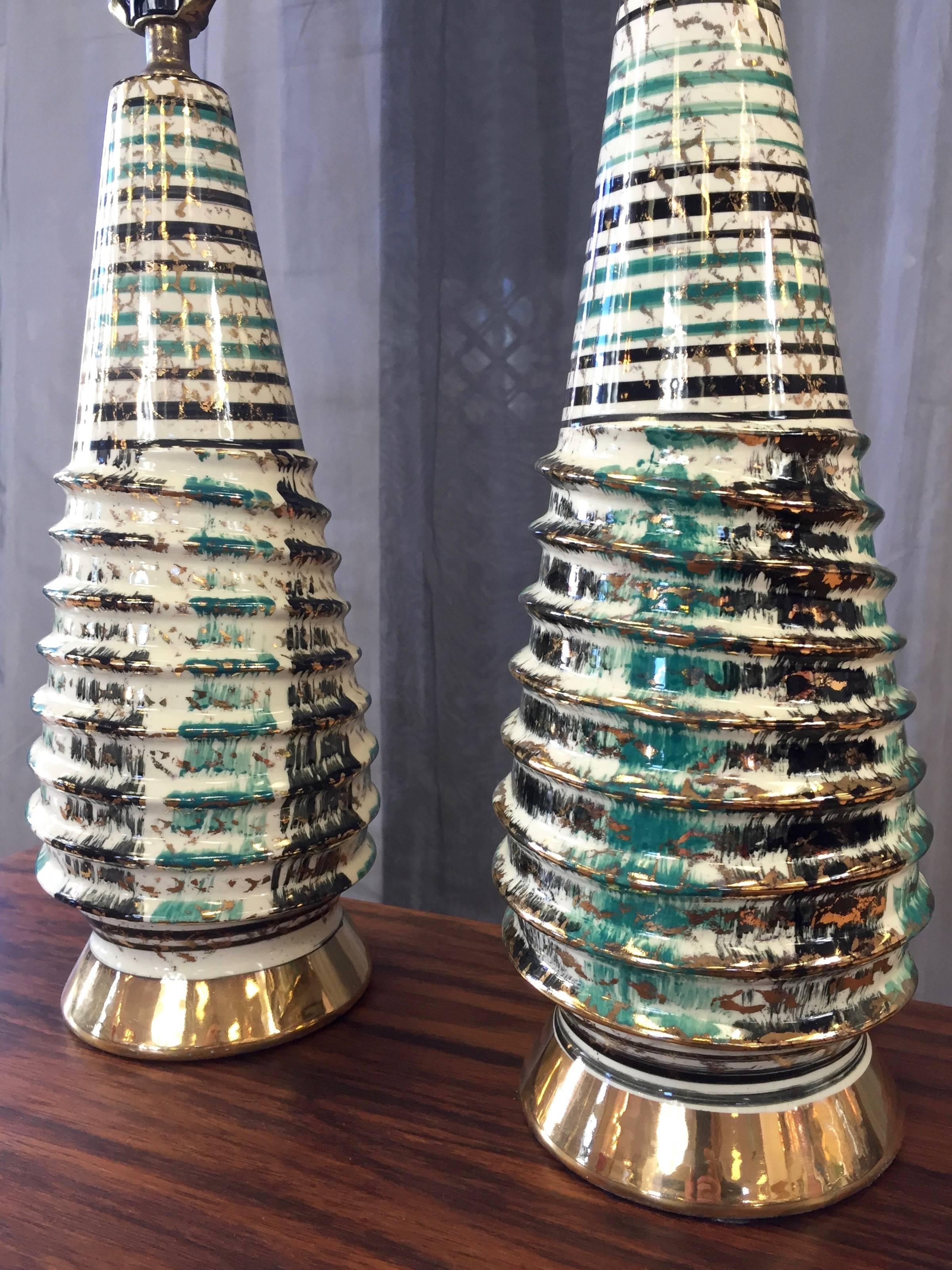 A Mid-Century Modern or Hollywood Regency pair of tall ceramic table lamps with sculptural bodies and hand-applied glaze.

Uncommon and handsome screw-like form is finished in off-white with painterly black, teal, and gleaming gold decoration.