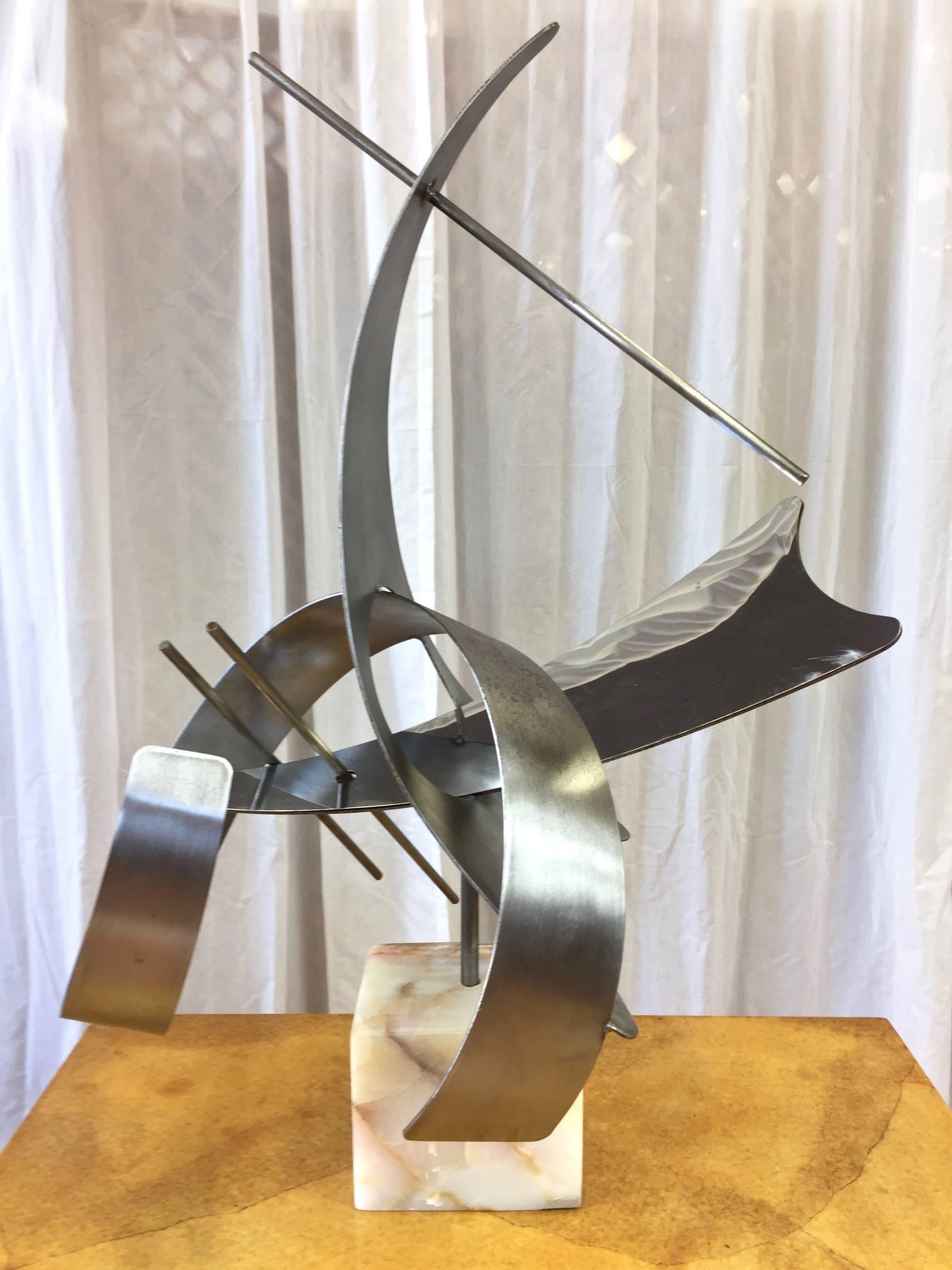 An impressively scaled vintage abstract steel sculpture on onyx base by Curtis Jeré.

Intersecting assemblage of wings, ribbons, and rods gives the stationary piece an exceptionally Kinetic aesthetic that holds visual interest from every angle.