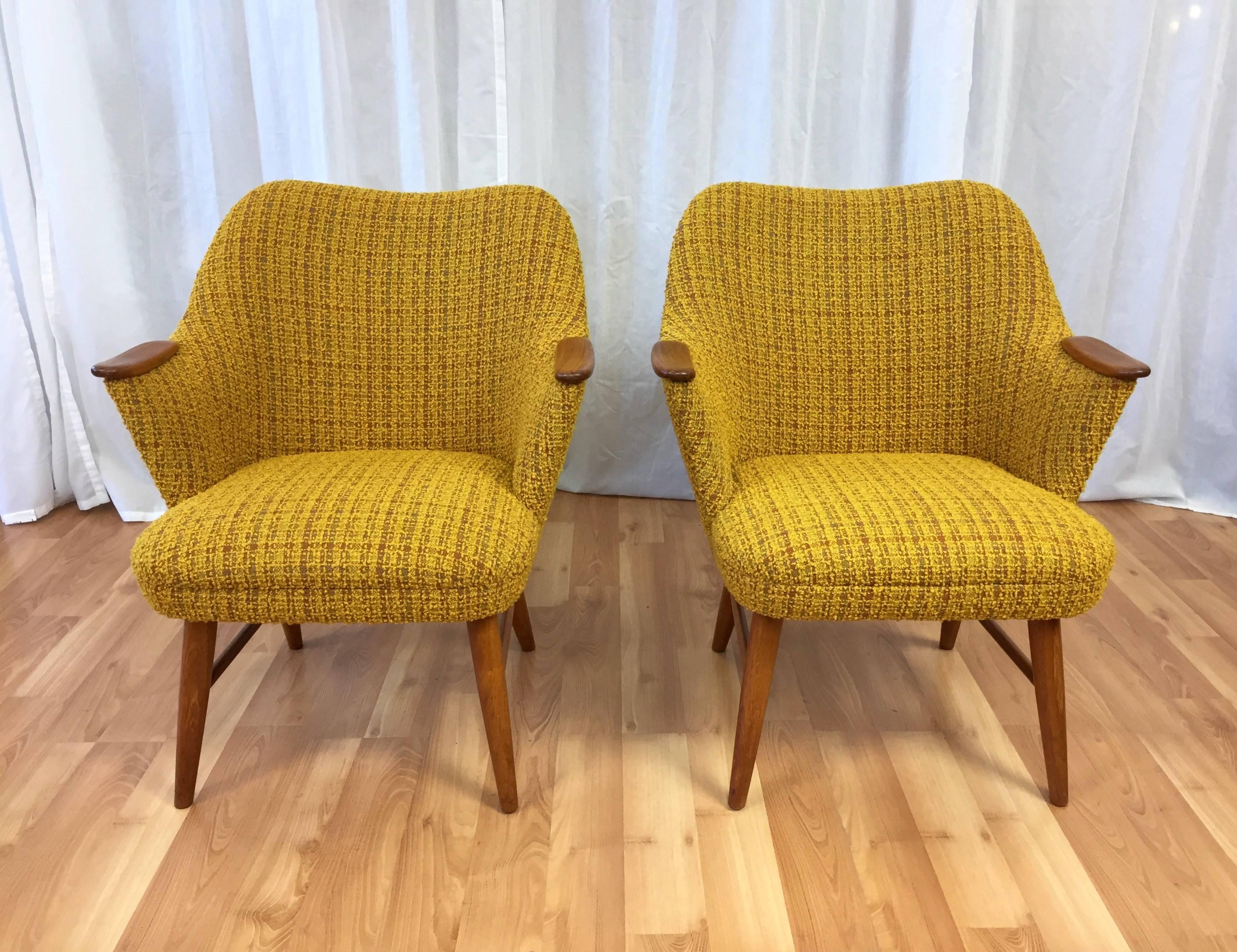 A delightful pair of smaller-scale upholstered Danish armchairs with teak accents.

Broad, nicely pitched seat backs flow into arms topped with hand-carved teak “surfboard” accents. Sits low on solid teak dowel legs. Original wool blend bouclé́