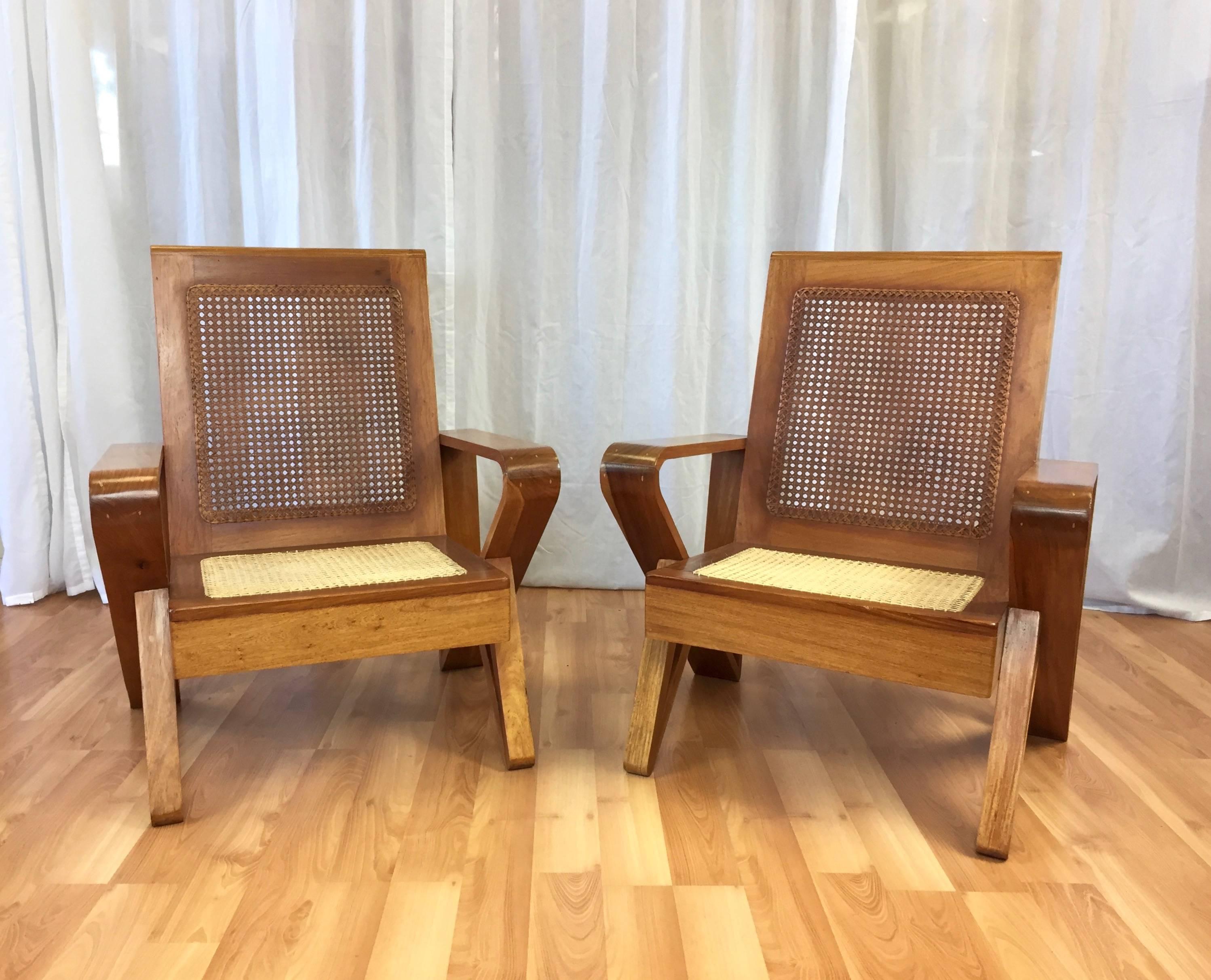 A stately pair of uncommon Hawaiian lounge chairs in solid koa wood with woven cane seats and backs.

Fantastic lines on these circa 1940s low lounge chairs, with a thoroughly modern geometric design to their arms and legs. Displays warm and rich