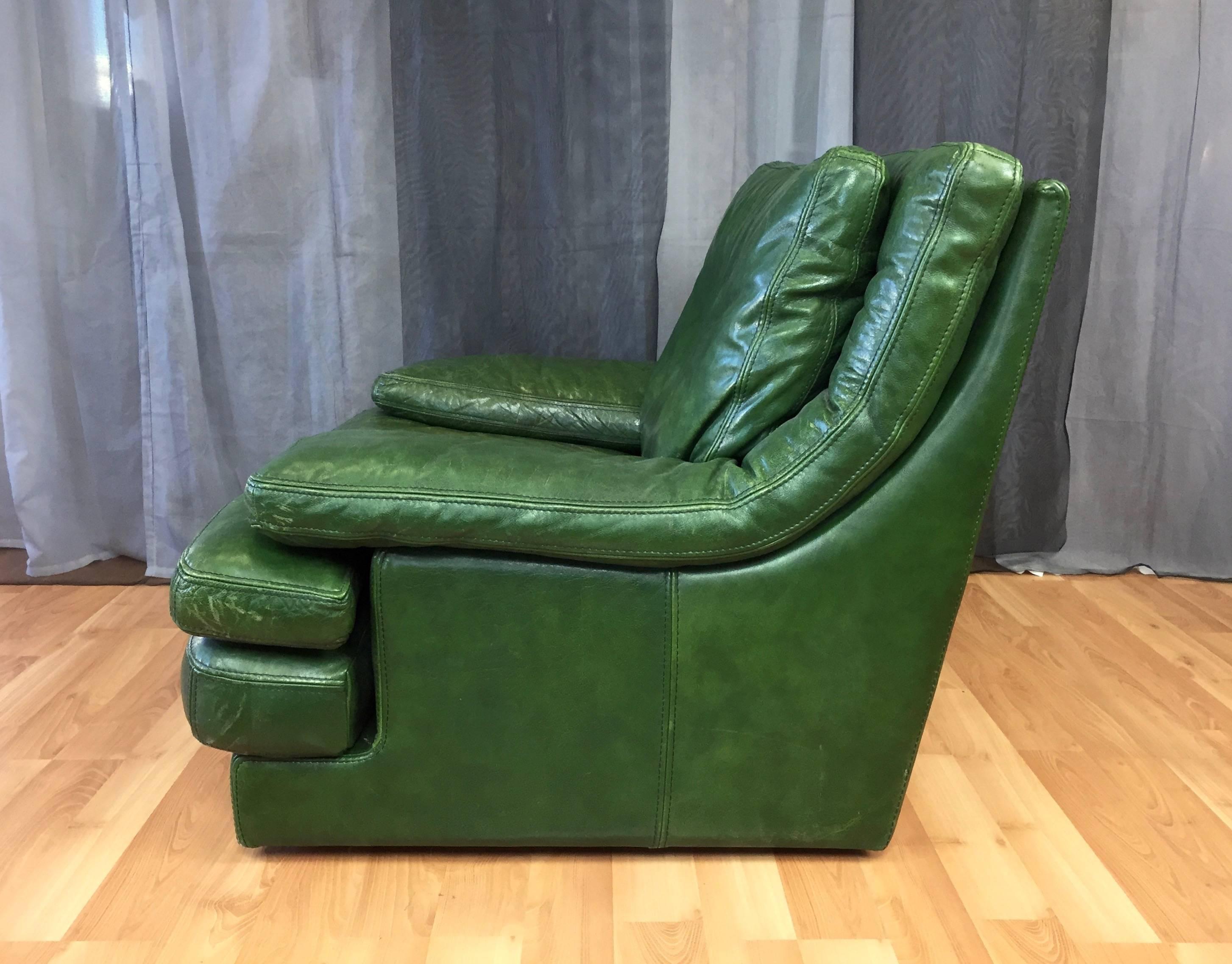 An oversized and extremely comfortable vintage Roche Bois leather lounge chair in British racing green. Stacked low profile base, seat cushions, and armrests present a casually modern design that’s very inviting. Extra-wide slab arms curve