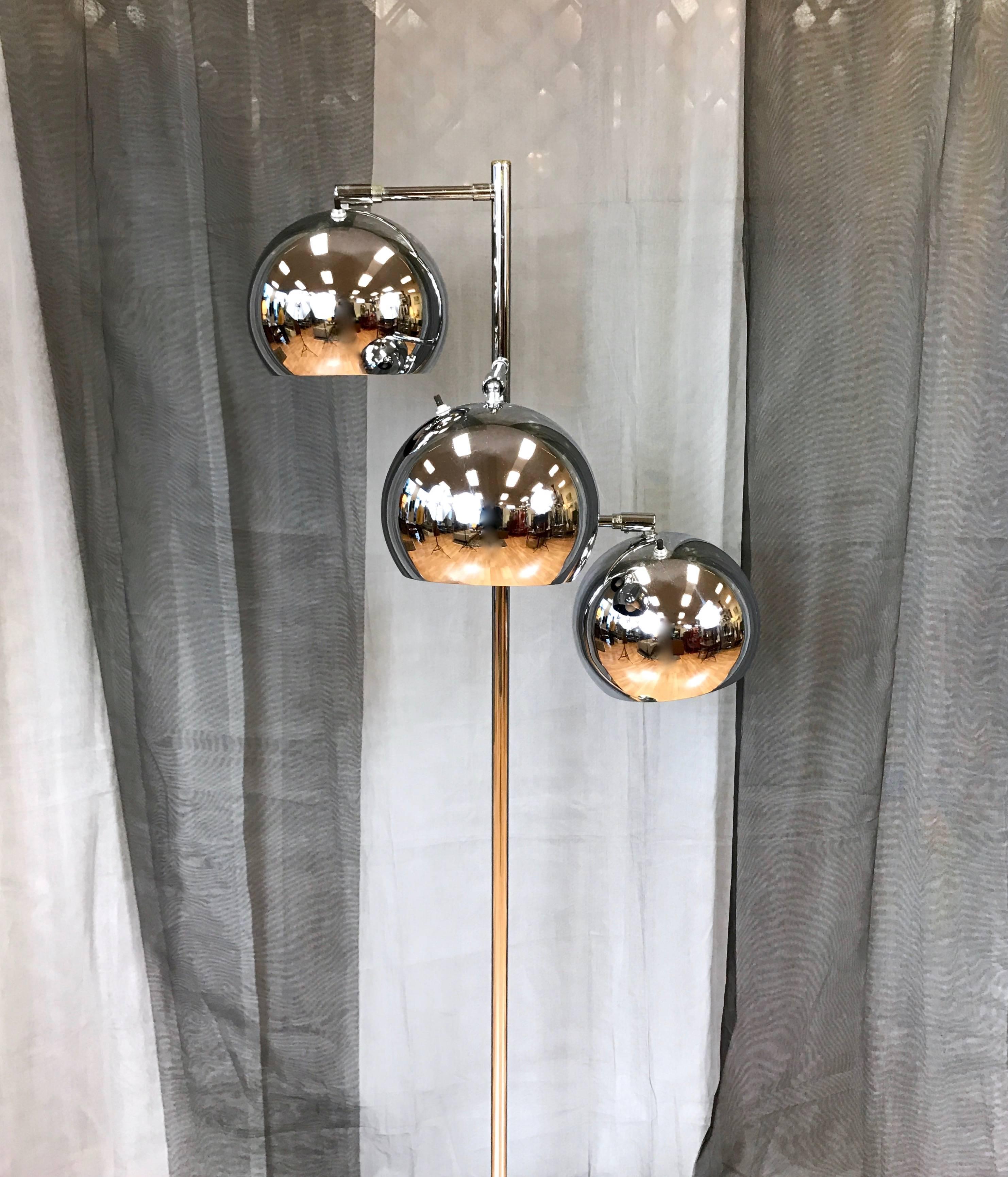 A chrome floor lamp with articulated shades by OMI for Koch & Lowy. Large “eyeball”-style globe shades swivel up and down via ball joints, and have matte black interiors. They’re slightly larger in diameter than those found on similar lamps by