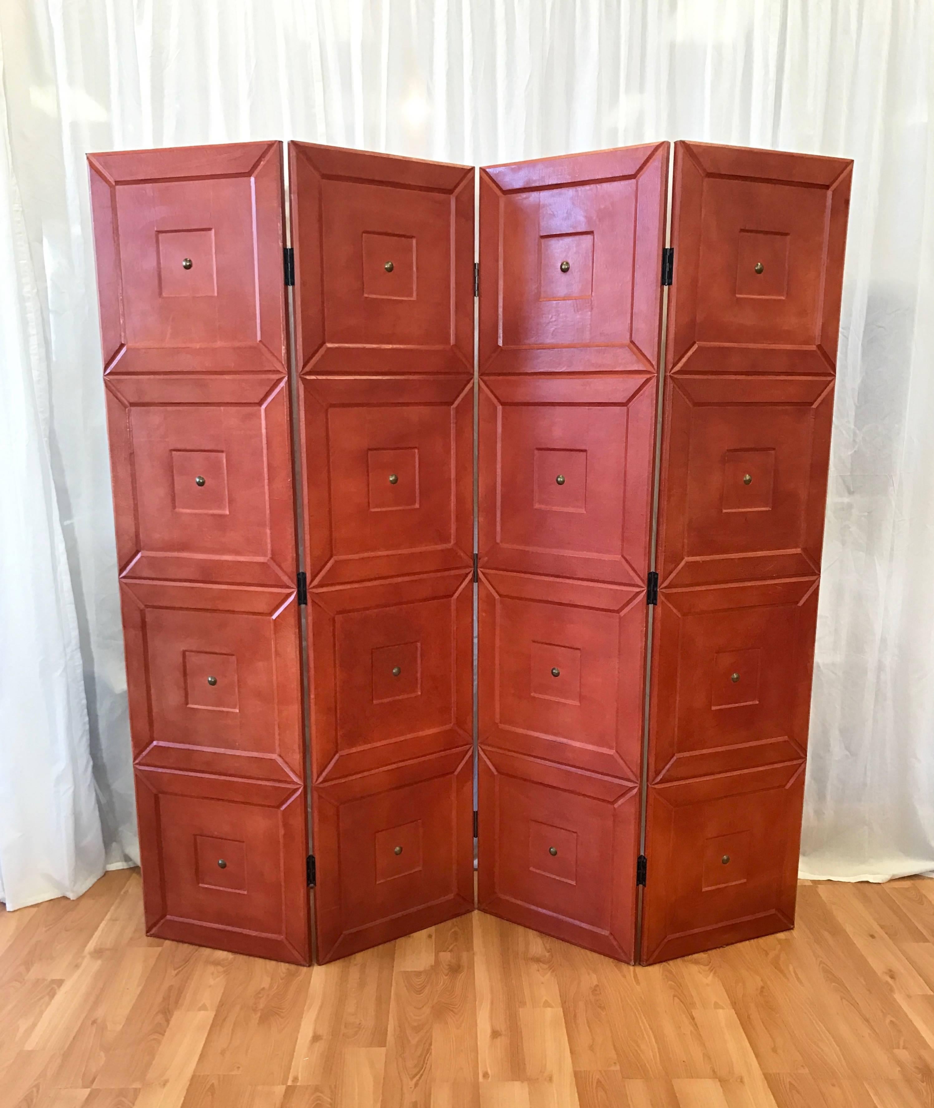 A freestanding four-panel wood folding screen or room divider in leather with brass details by Maitland-Smith. Beveled and stepped design is completely and meticulously covered in richly hued aniline pig Napa. Features large brass brad decorations