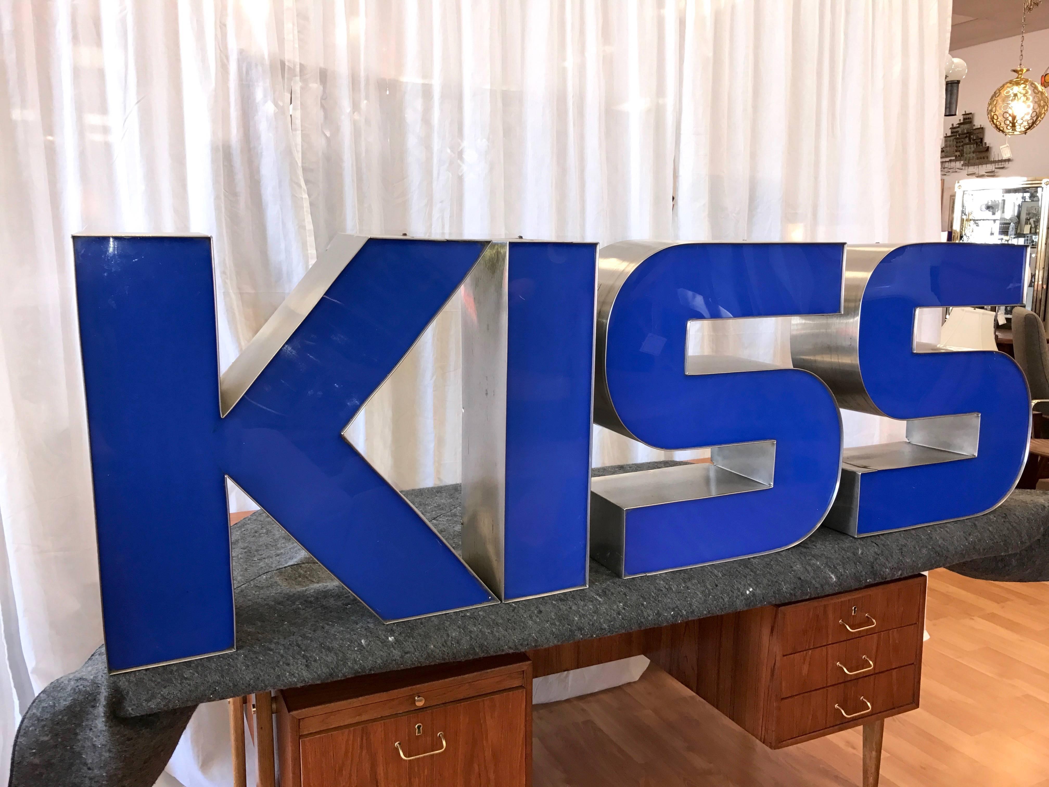 A set of four large vintage indoor or outdoor metal and acrylic signage letters that spell “KISS” by Tennessee-based Plasti-Line Inc.

Bold, graphic letters have brushed sheet metal frames and royal blue plexiglass faces. Deep, sturdy, and stable
