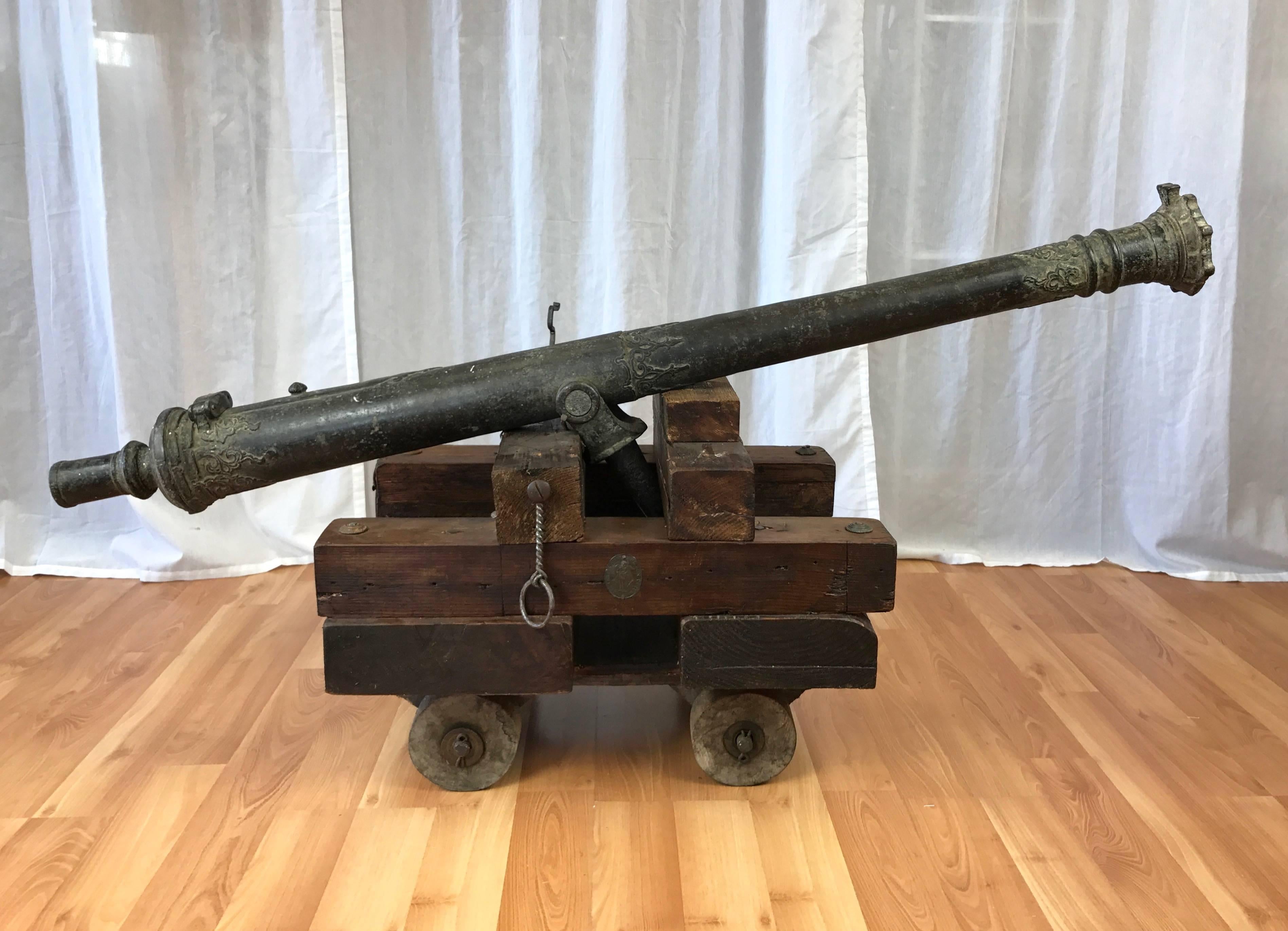 An 18th century patinated bronze lantaka cannon from South East Asia on custom-made functional wood carriage.

Medallion-shaped muzzle nicely complements raised filigree ornamentation around the upper chase, girdle, vent and breech. Trunnion is