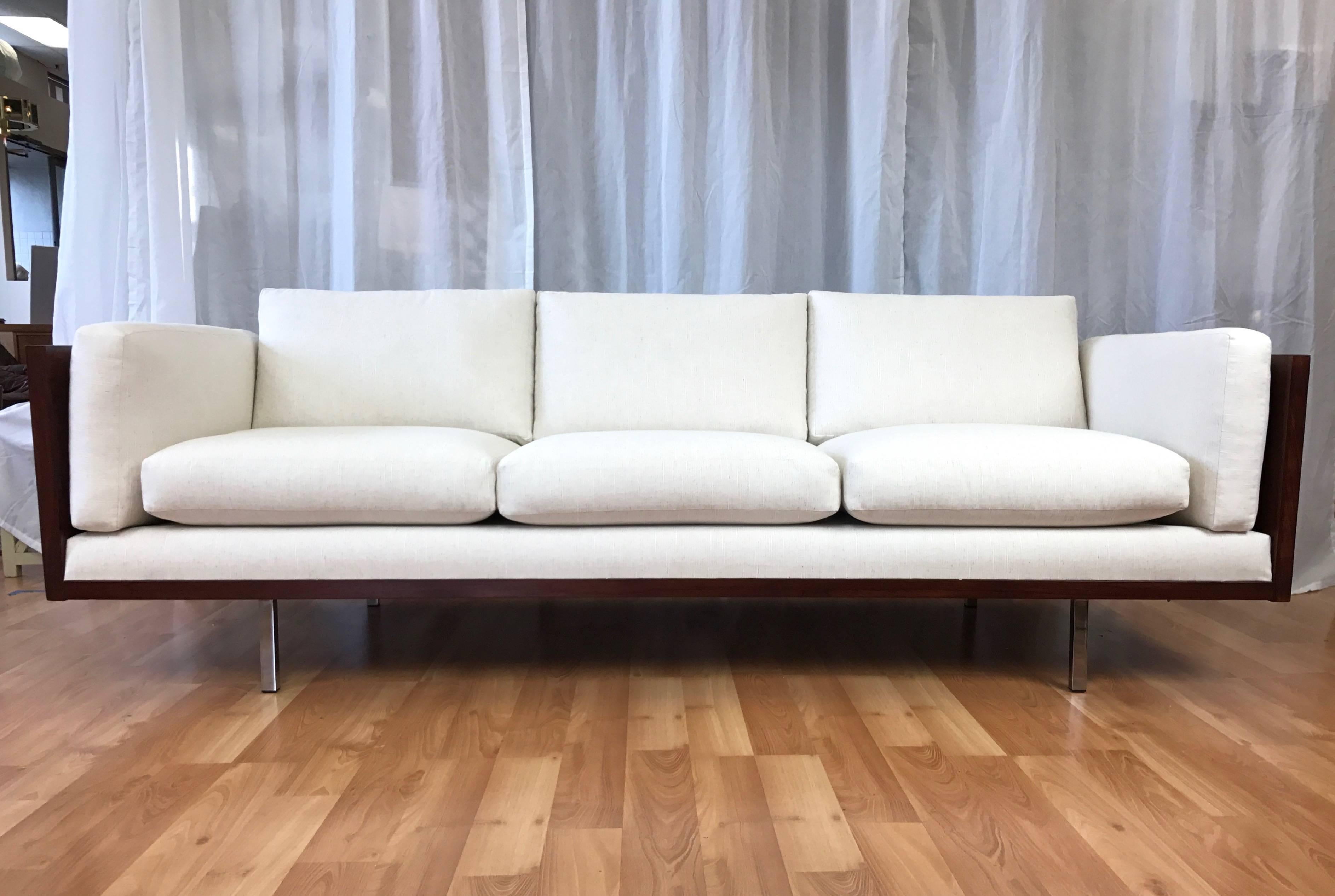 A rare extra-long Danish Rosewood case sofa by Komfort
with new upholstery (also known as a clad box sofa).

Three-panel wood frame is finished in a stunning wraparound expanse of bookmatched rosewood veneer on the back and both sides of the arms.