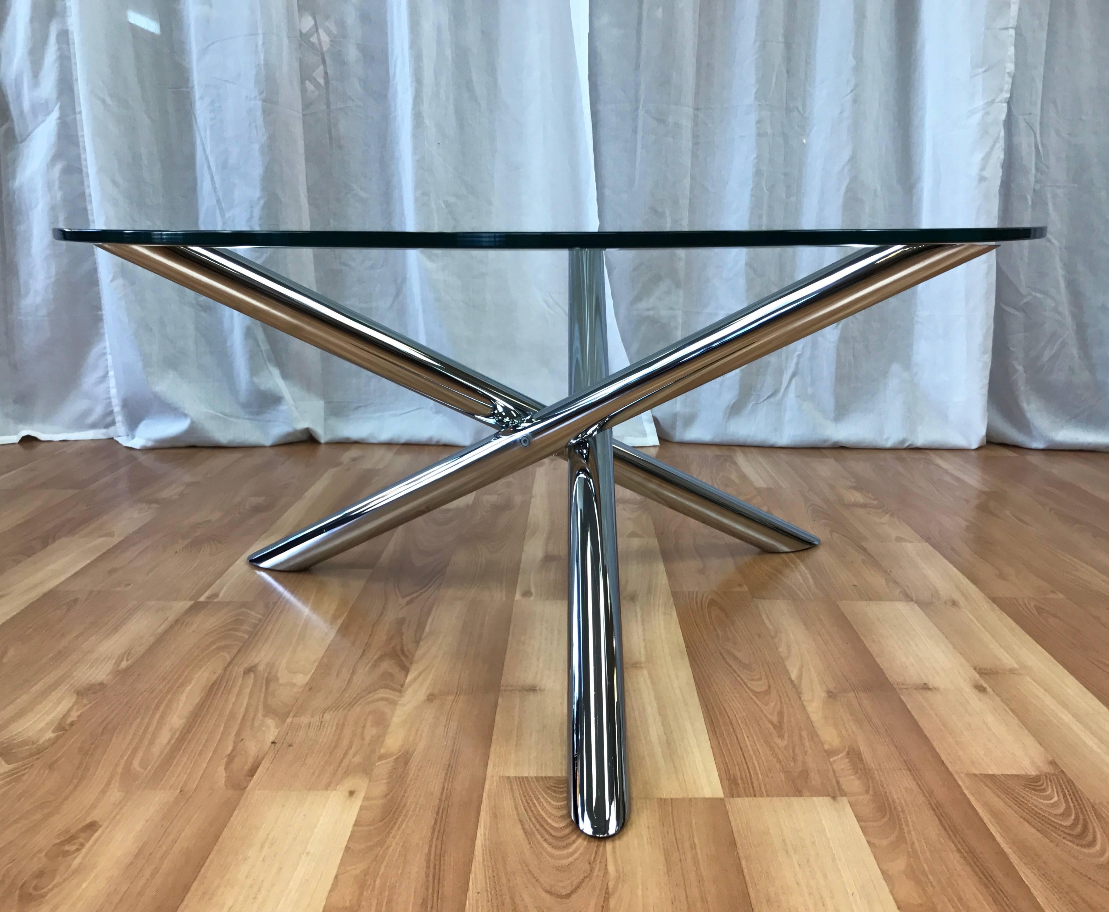 A large vintage coffee or cocktail table with tripod chrome base and round glass top in the style of Milo Baughman and Pace Collection.

Minimalist star-shaped base comprised of three long, chrome-plated steel tubes splayed around a small