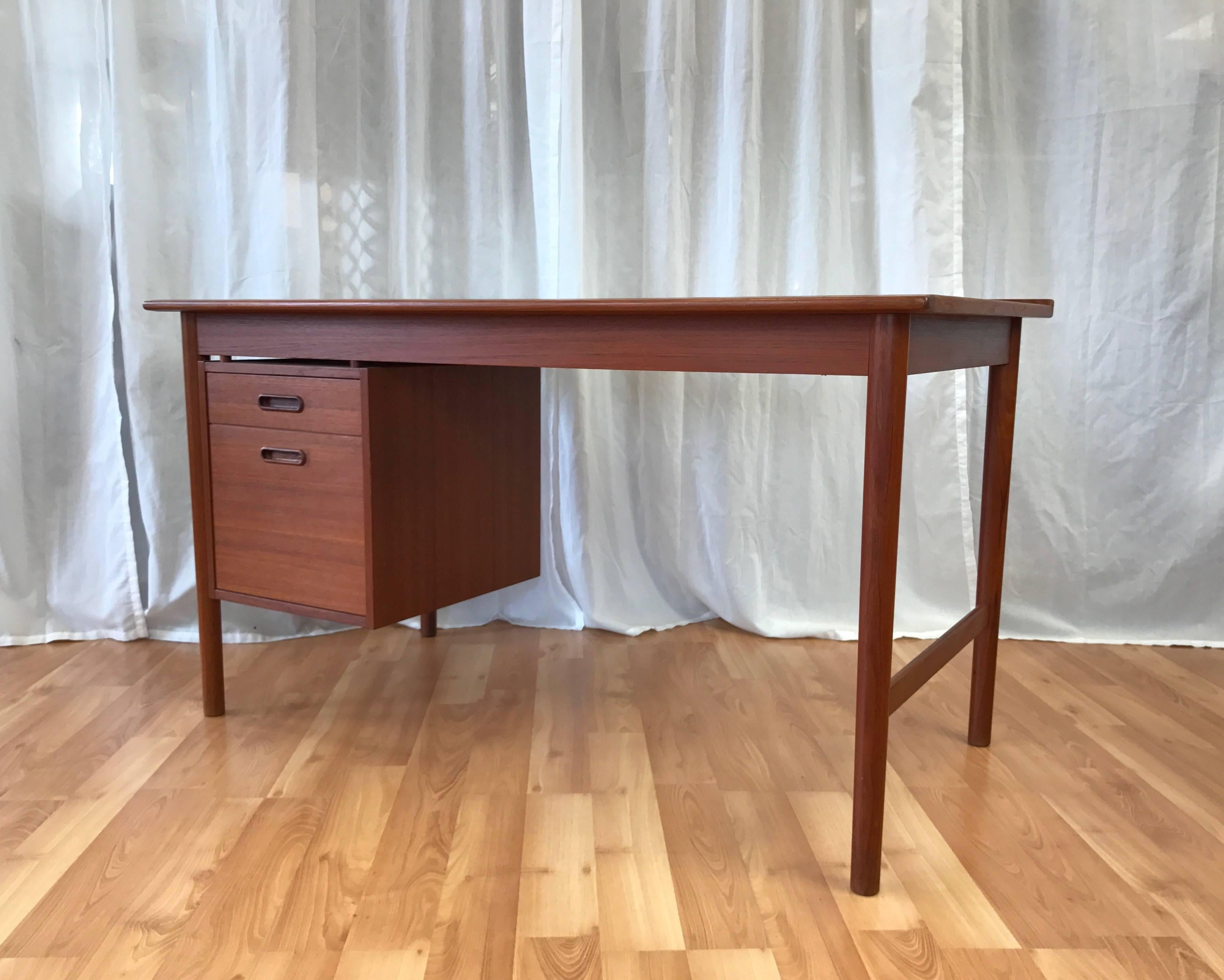 A Danish Modern “Model 541” teak writing desk by Folke Ohlsson for DUX.

Clean-lined floating cabinet holds two drawers with solid teak recessed pulls. Bottom drawer features carved tracks for easily hanging file folders. Back lip and tapered