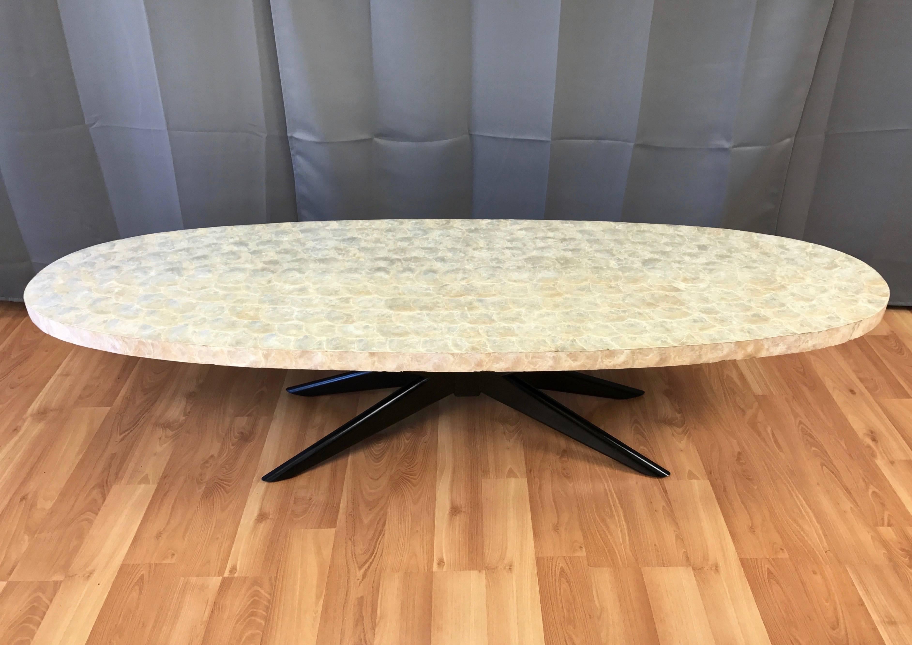 A fantastic Mid-Century extra-long surfboard coffee table with shimmering capiz shell top and black lacquered star-shaped “X” base.

Wood top is finished in artfully applied ivory-colored capiz shells. Satin black lacquered wood base is in the